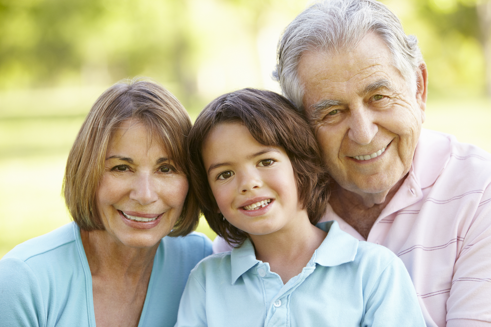 hispanic grandparents relaxing with grandchildren in park