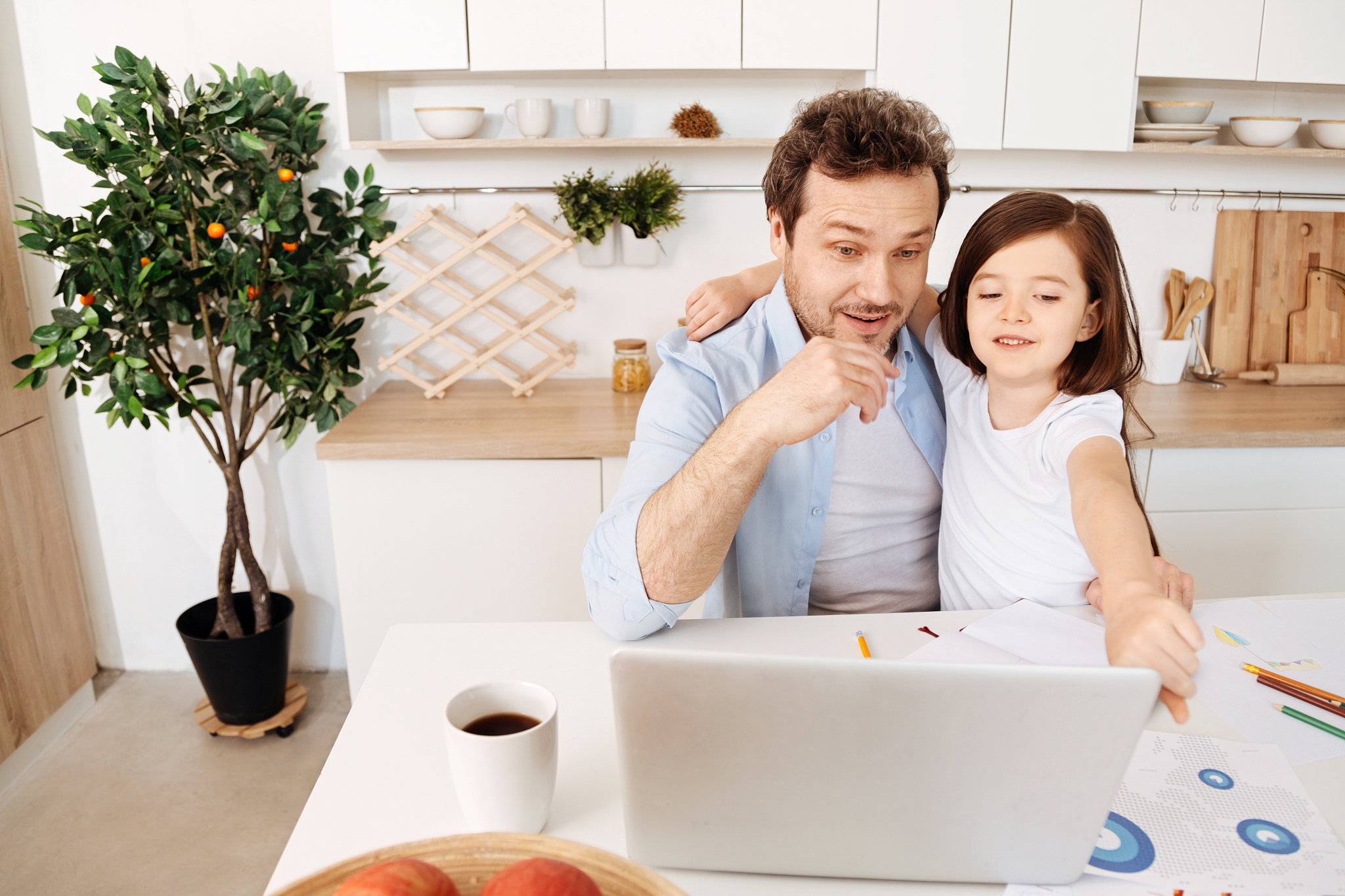 girl showing something amusing to her father on laptop