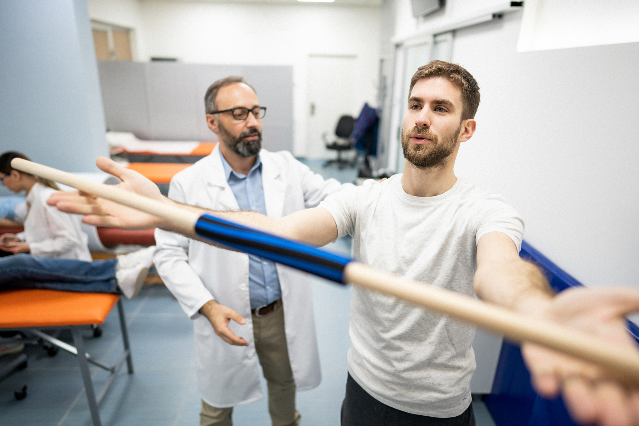 physiotherapist corrects the posture of his patient