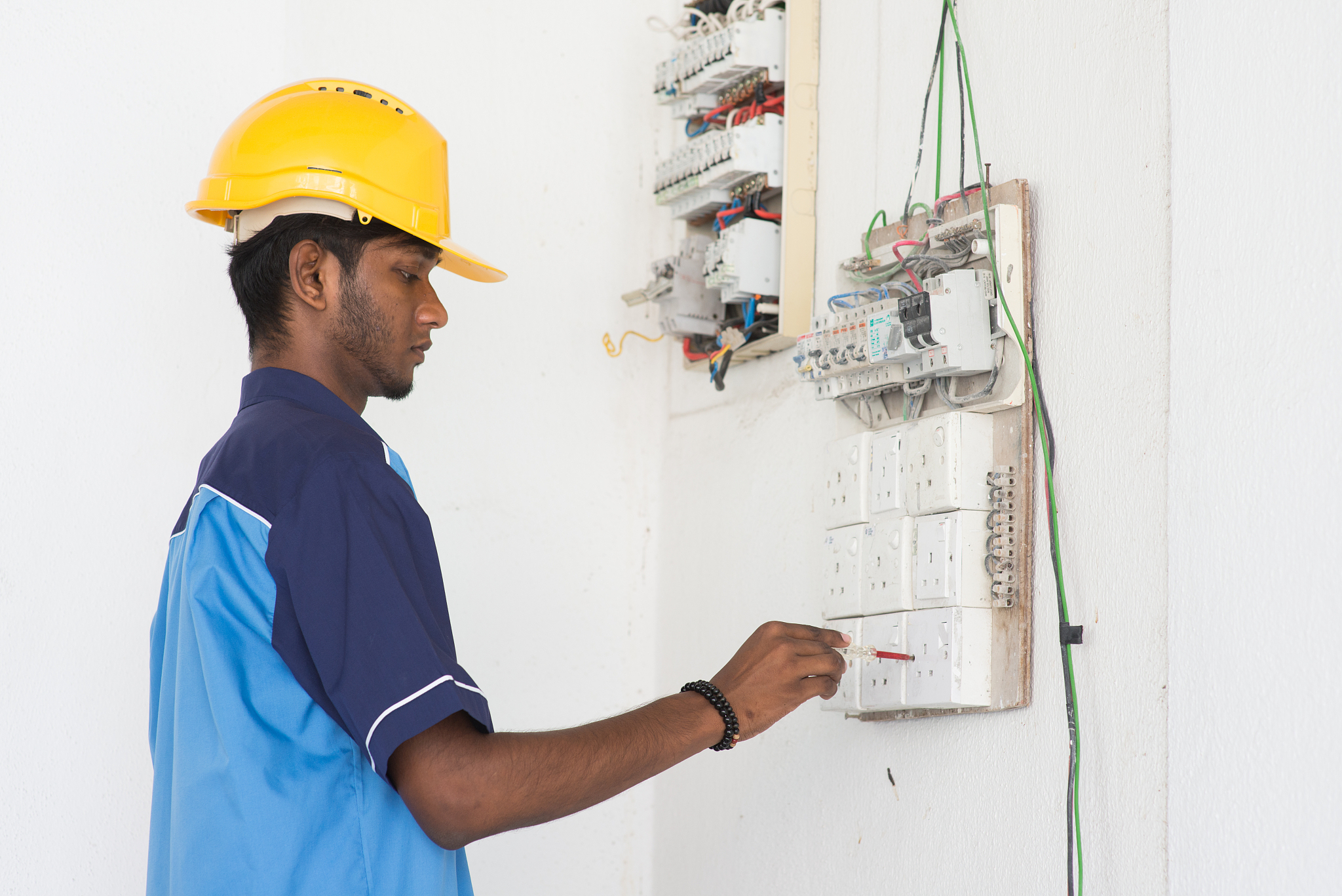 young man repairing electrical board on wall