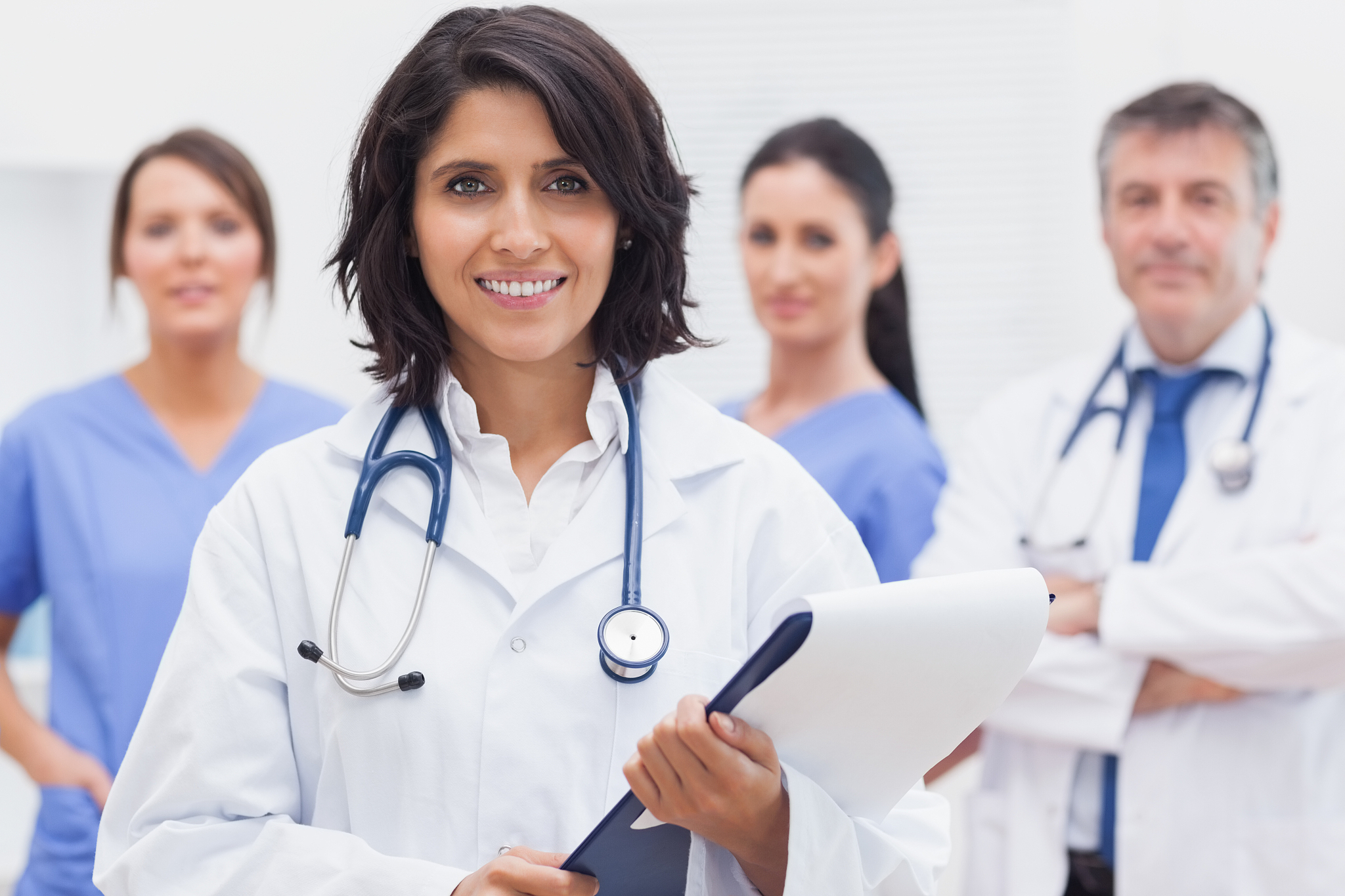 female doctor with clipboard and her team smiling