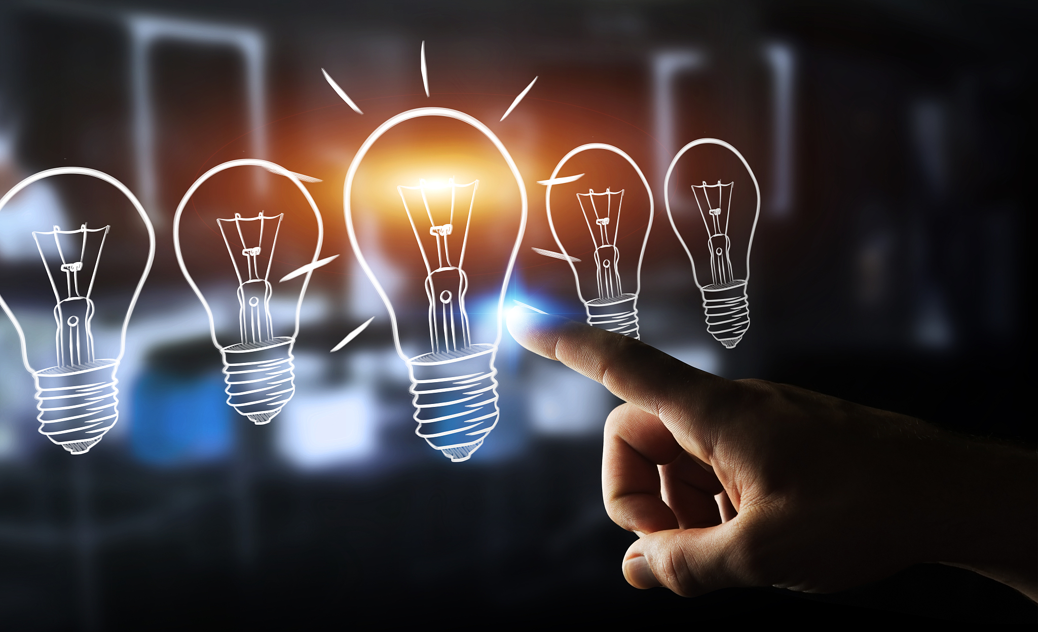 businessman on blurred background drawing a lightbulb with a pen