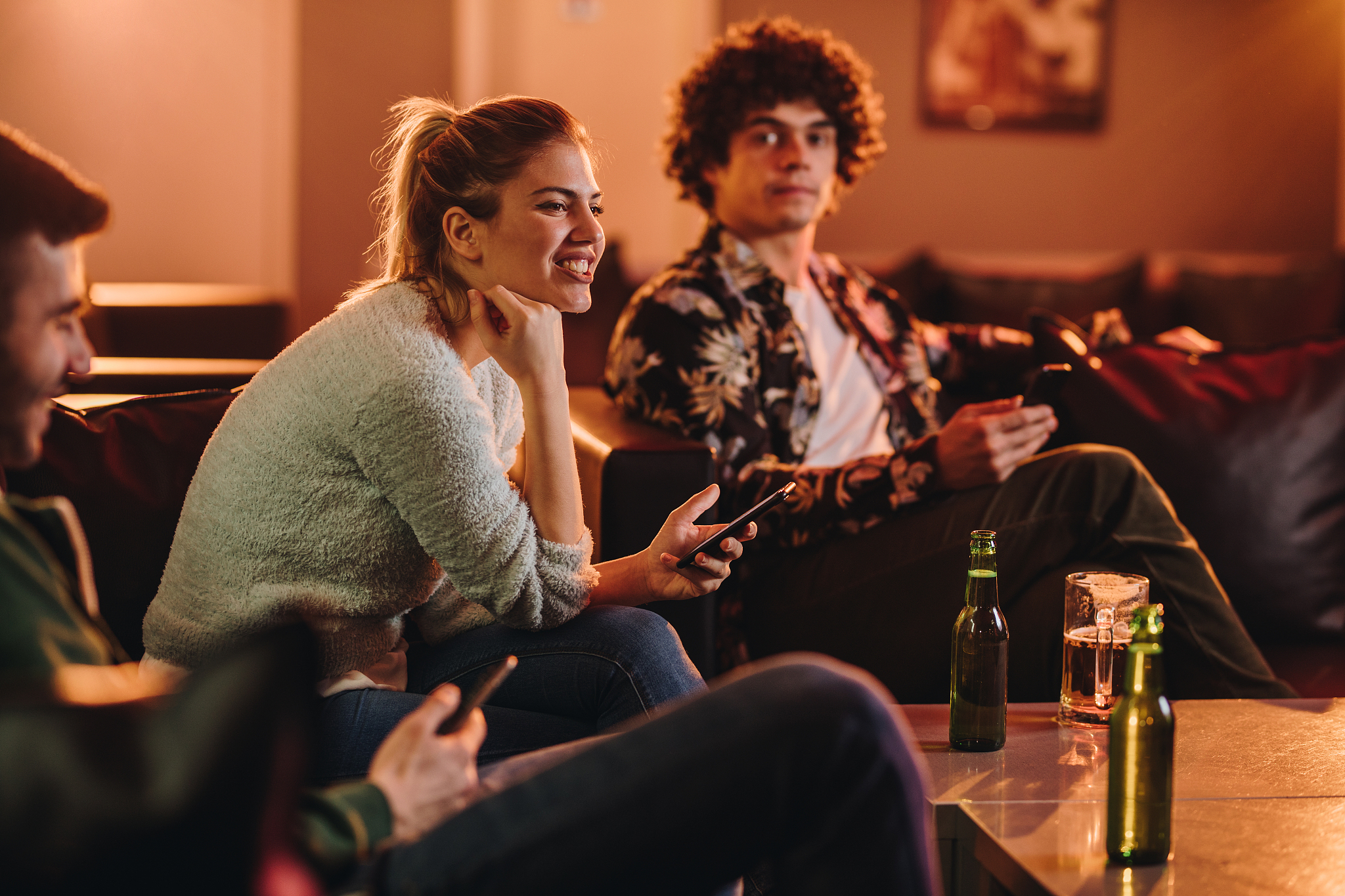 group of friends sitting in a bar and using cell phones.