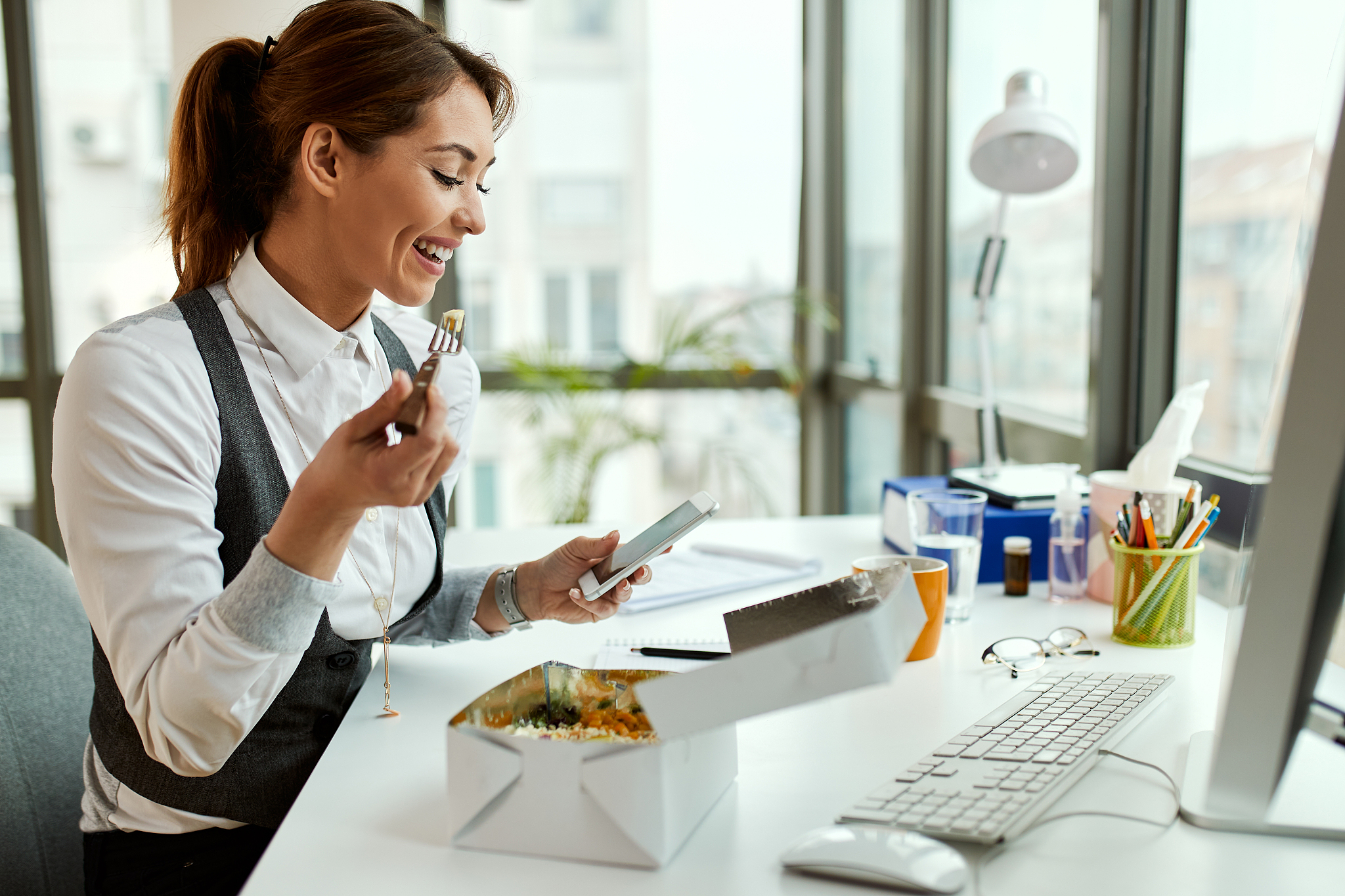 happy businesswoman using mobile phone on lunch break in the off