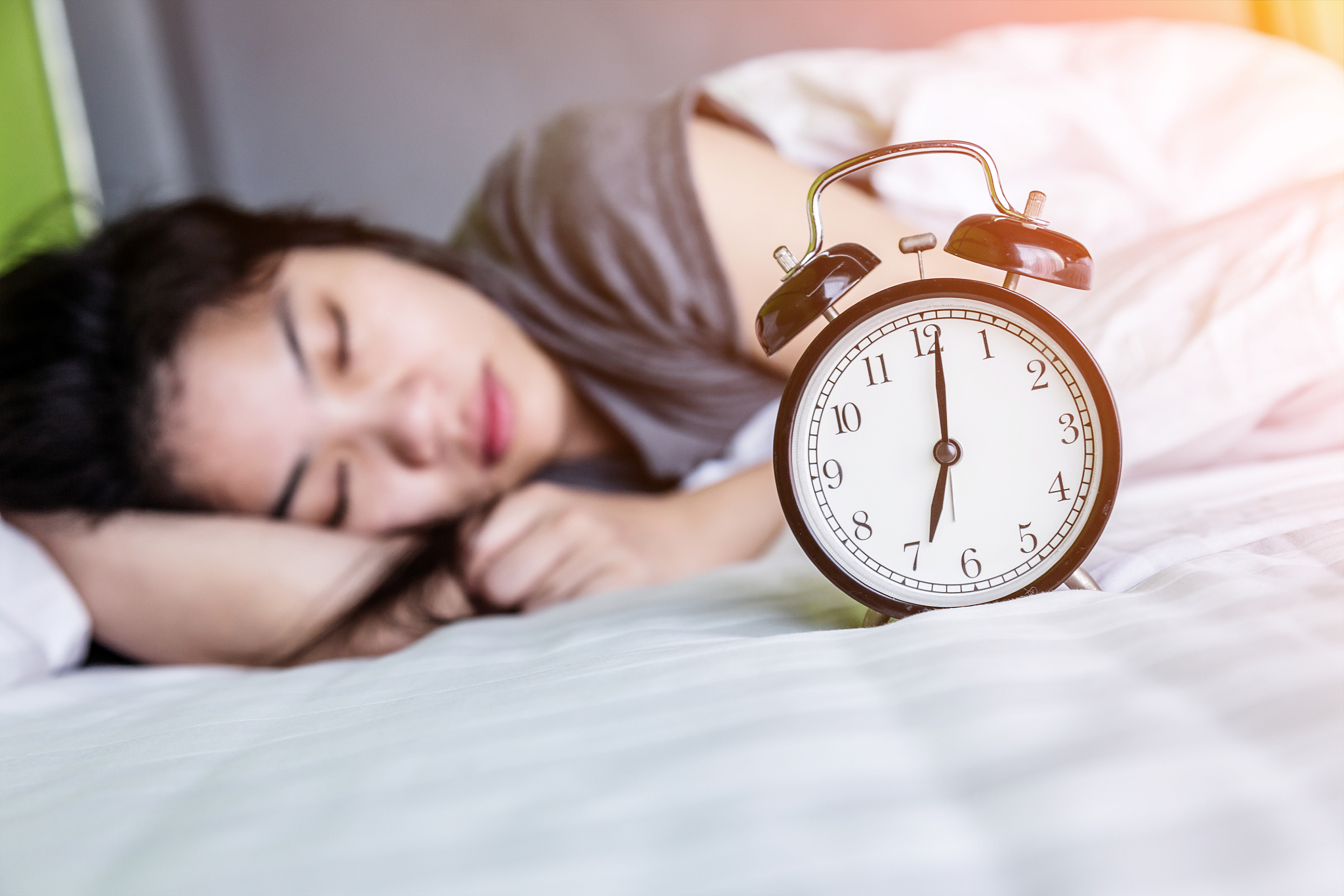 young sleeping woman and alarm clock in bedroom at home.