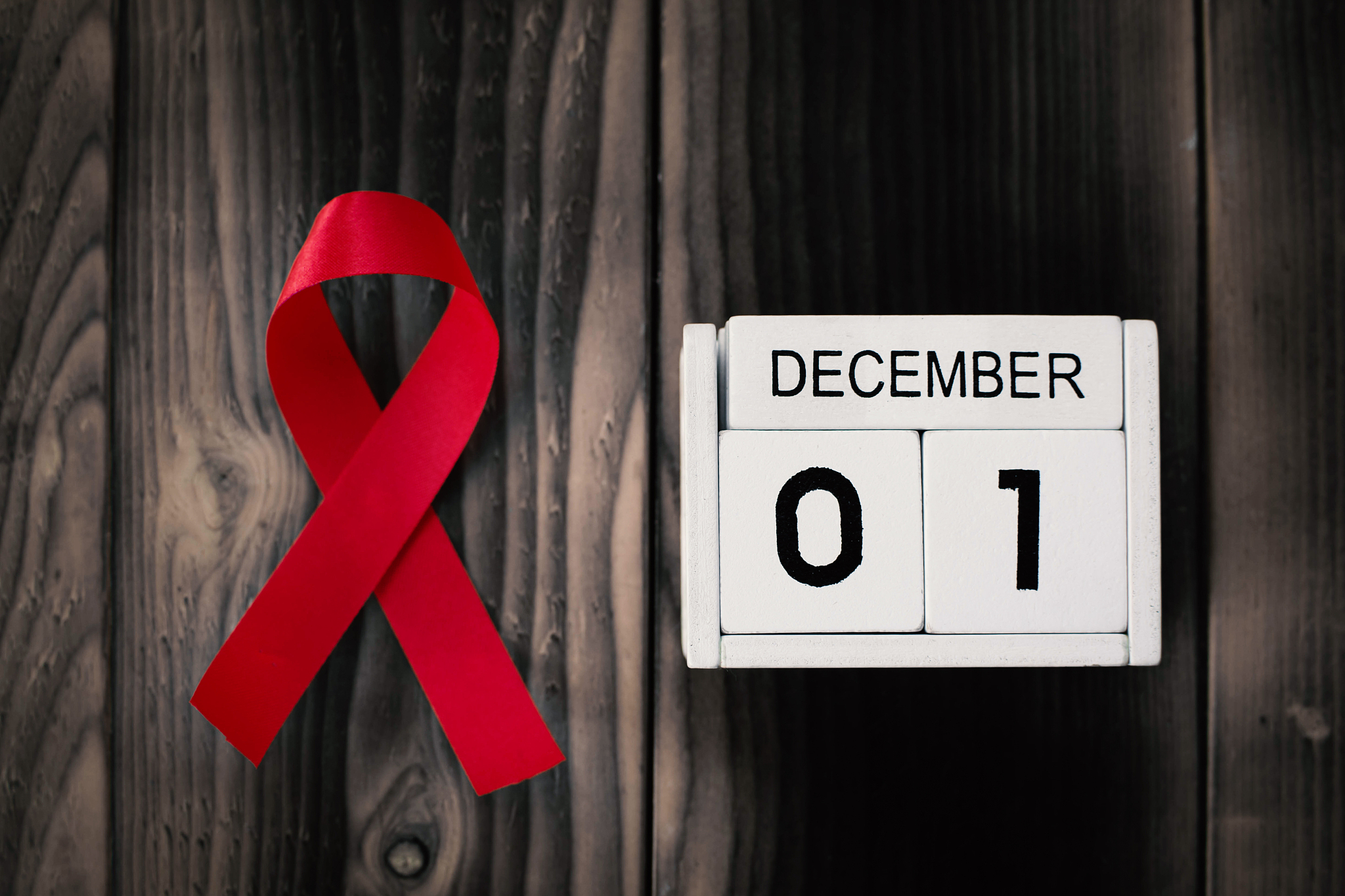 red ribbon with calendar date 1 december on brown wood backgroun