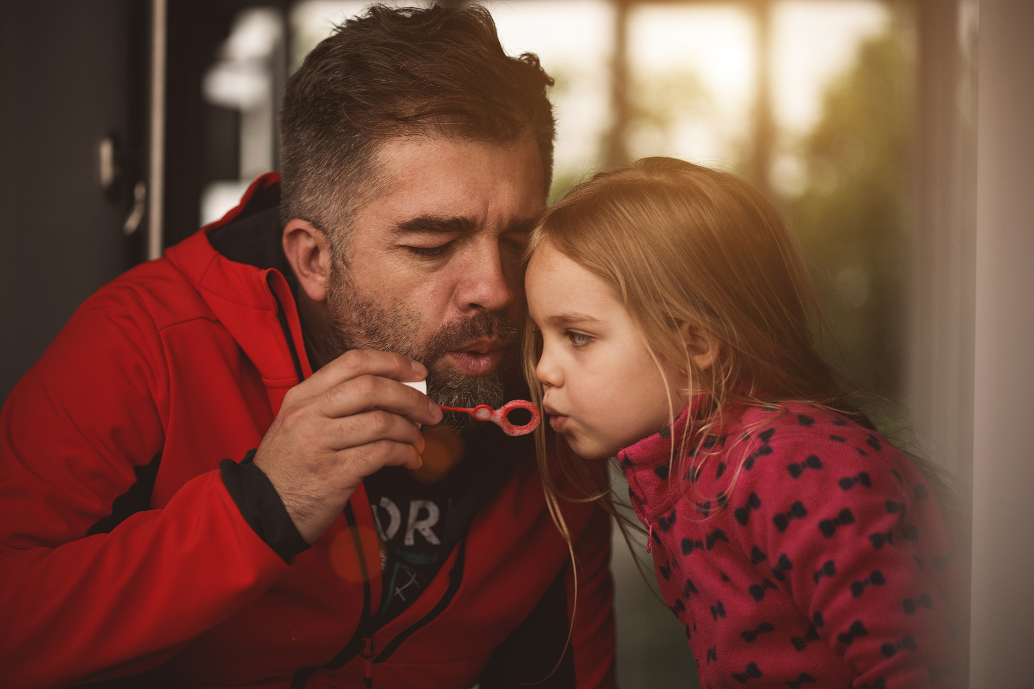 little girl blowing bubbles with her father