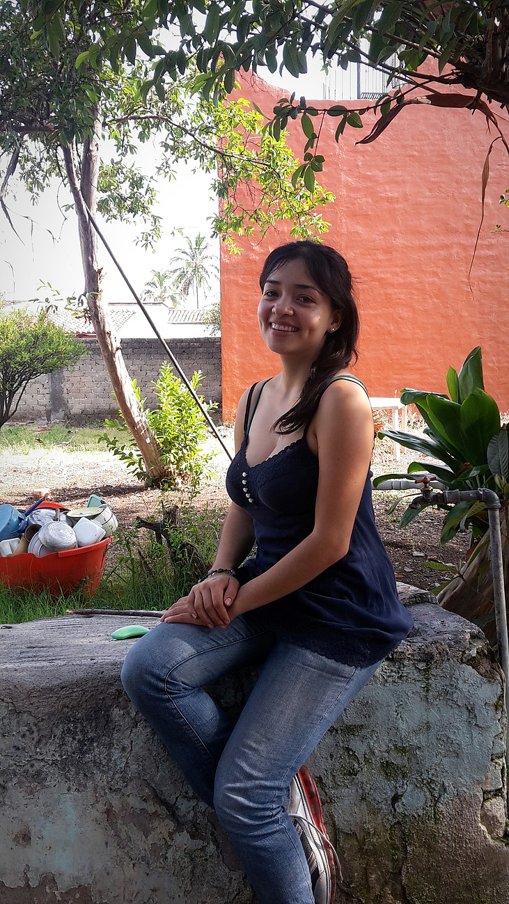 portrait of smiling young woman sitting on rock outdoors