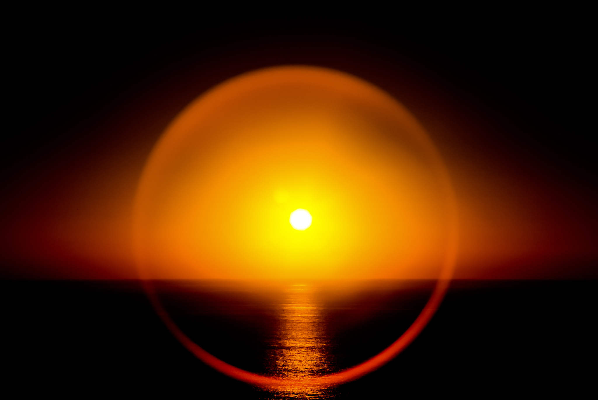 round glare around the sun at sunset in the sea. sunny sunset at