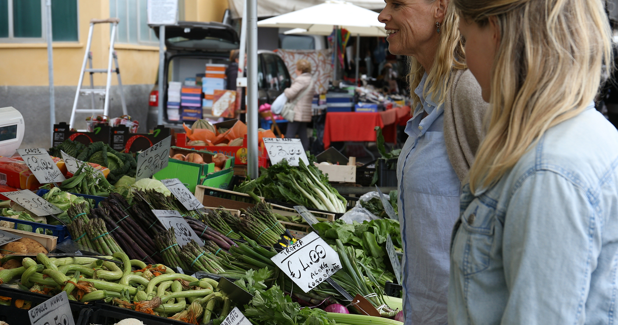 women buying vegetables at market stall