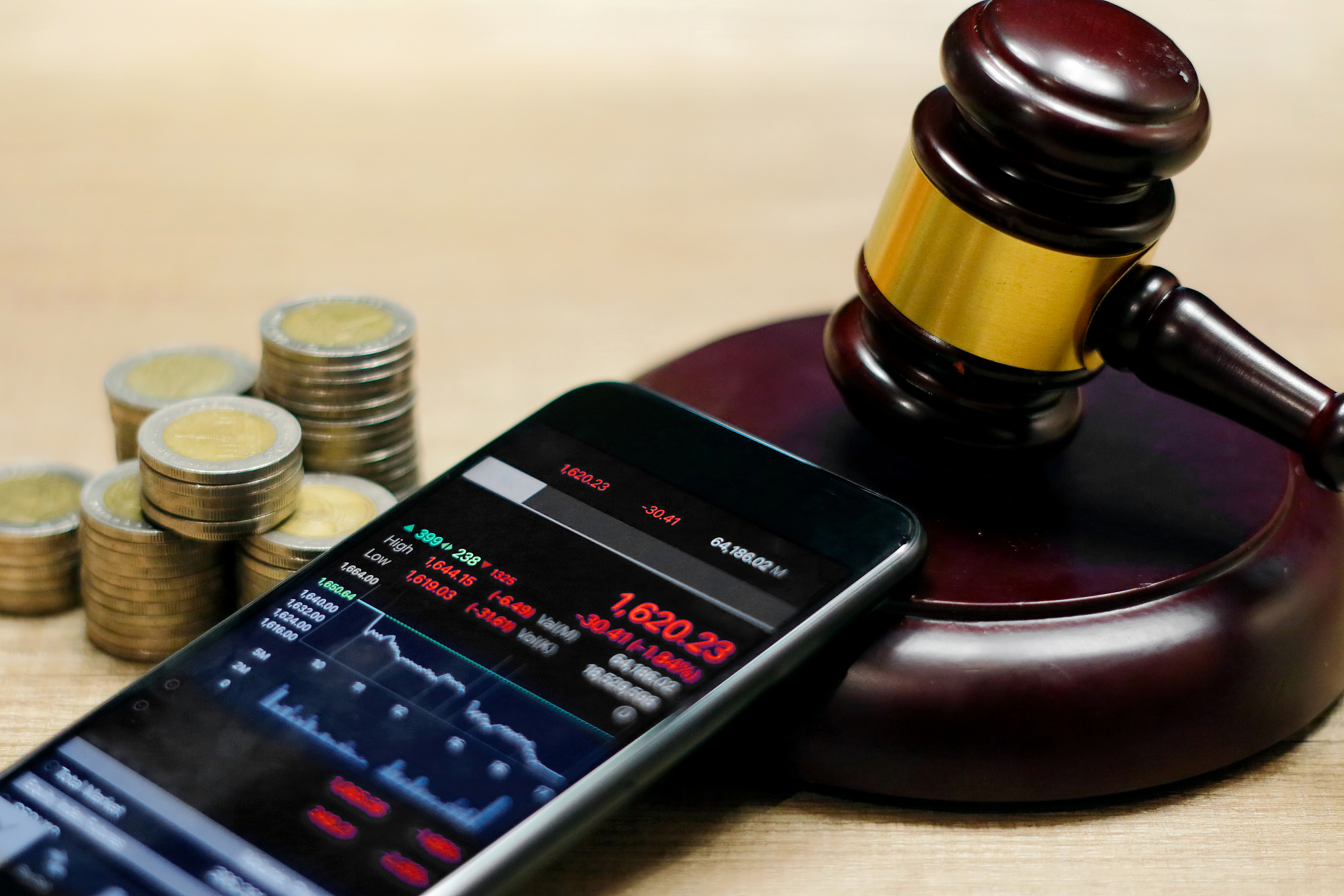 smartphone showing stock market trend and judge gavel, coin on t