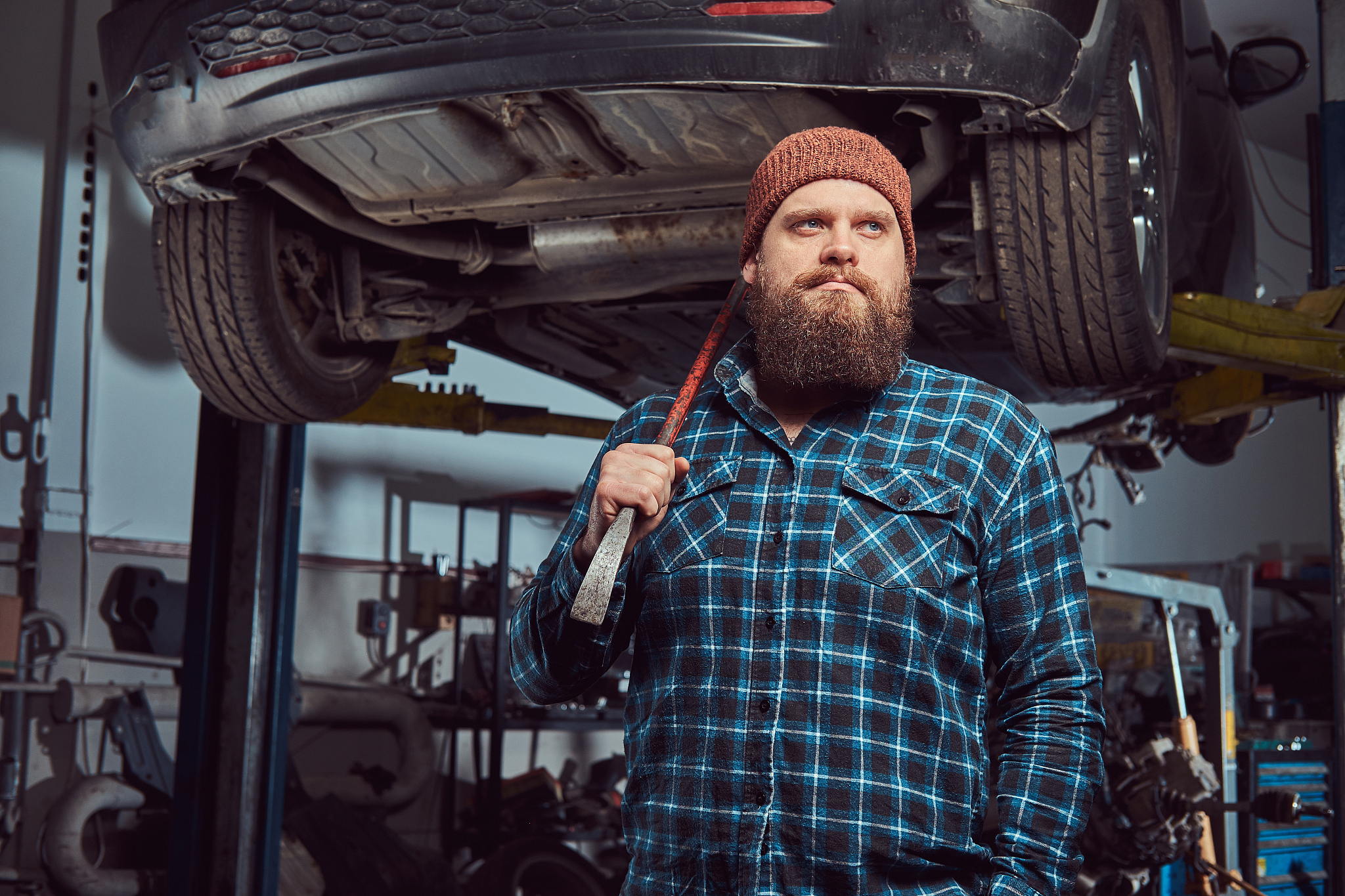 two bearded brutal mechanics repair a car on a lift in the garag
