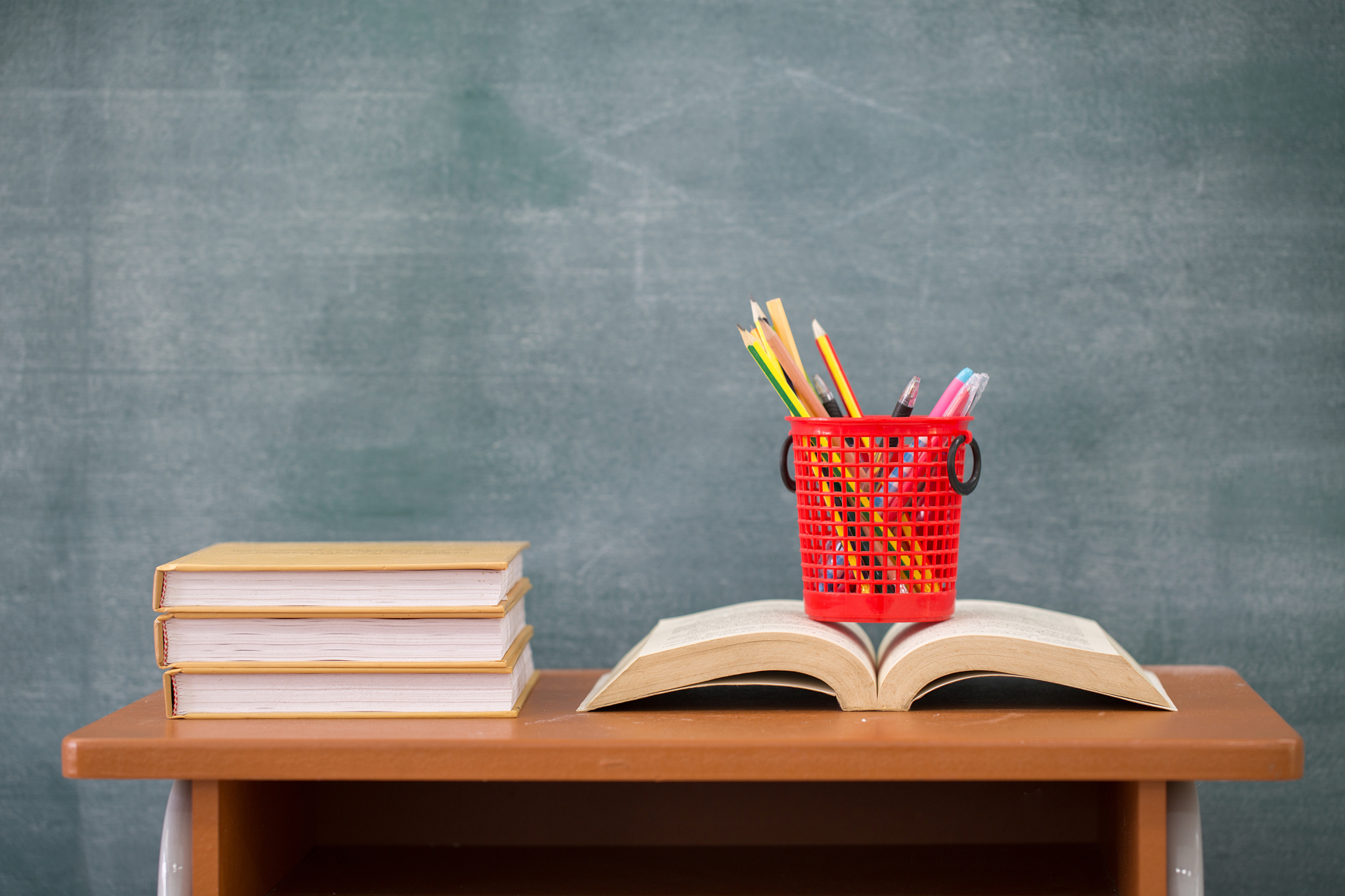 school books on desk, back to school supplies. books and blackbo