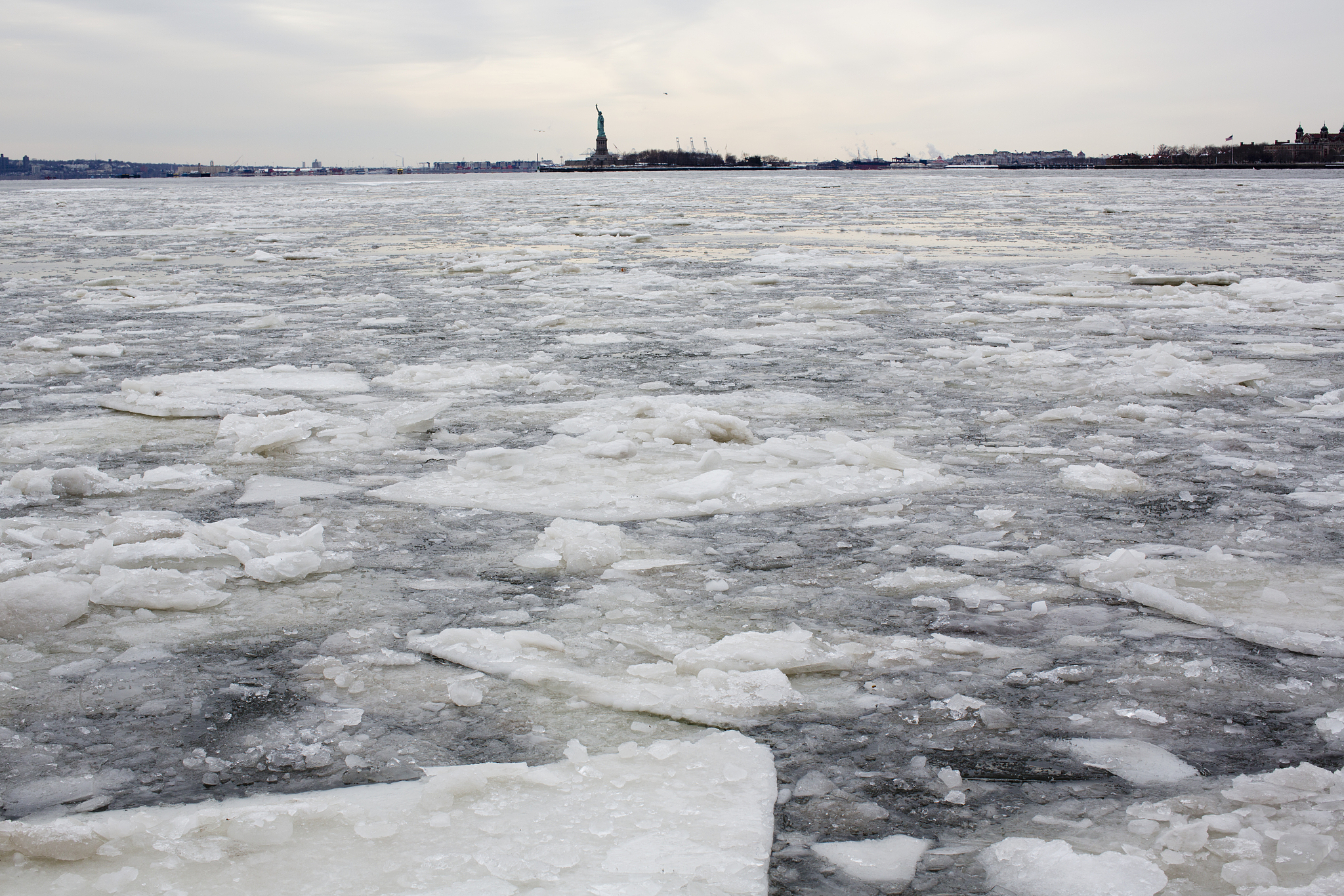 frozen river with statue of liberty on the horizon