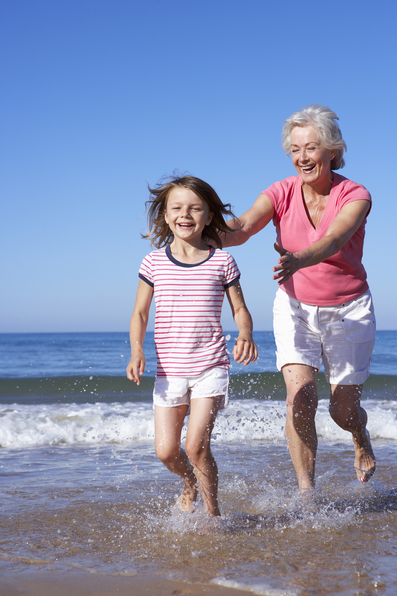 grandmother chasing granddaughter along beach