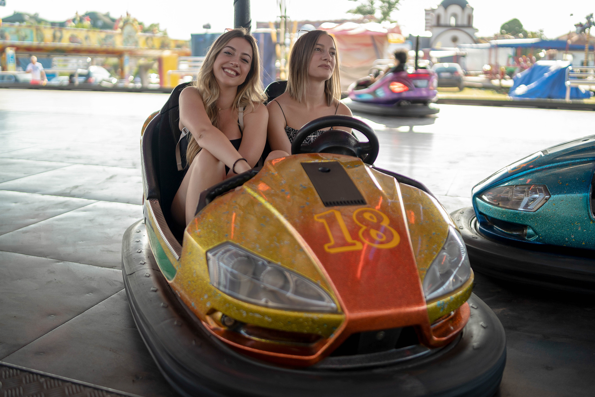happy girlfriends driving a bumper car and smiling