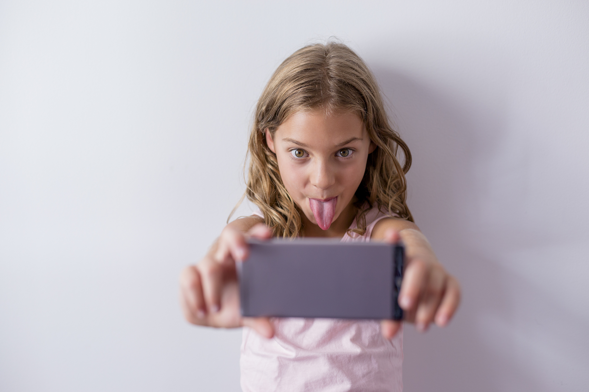 portrait of a young beautiful kid using a mobile phone and takin