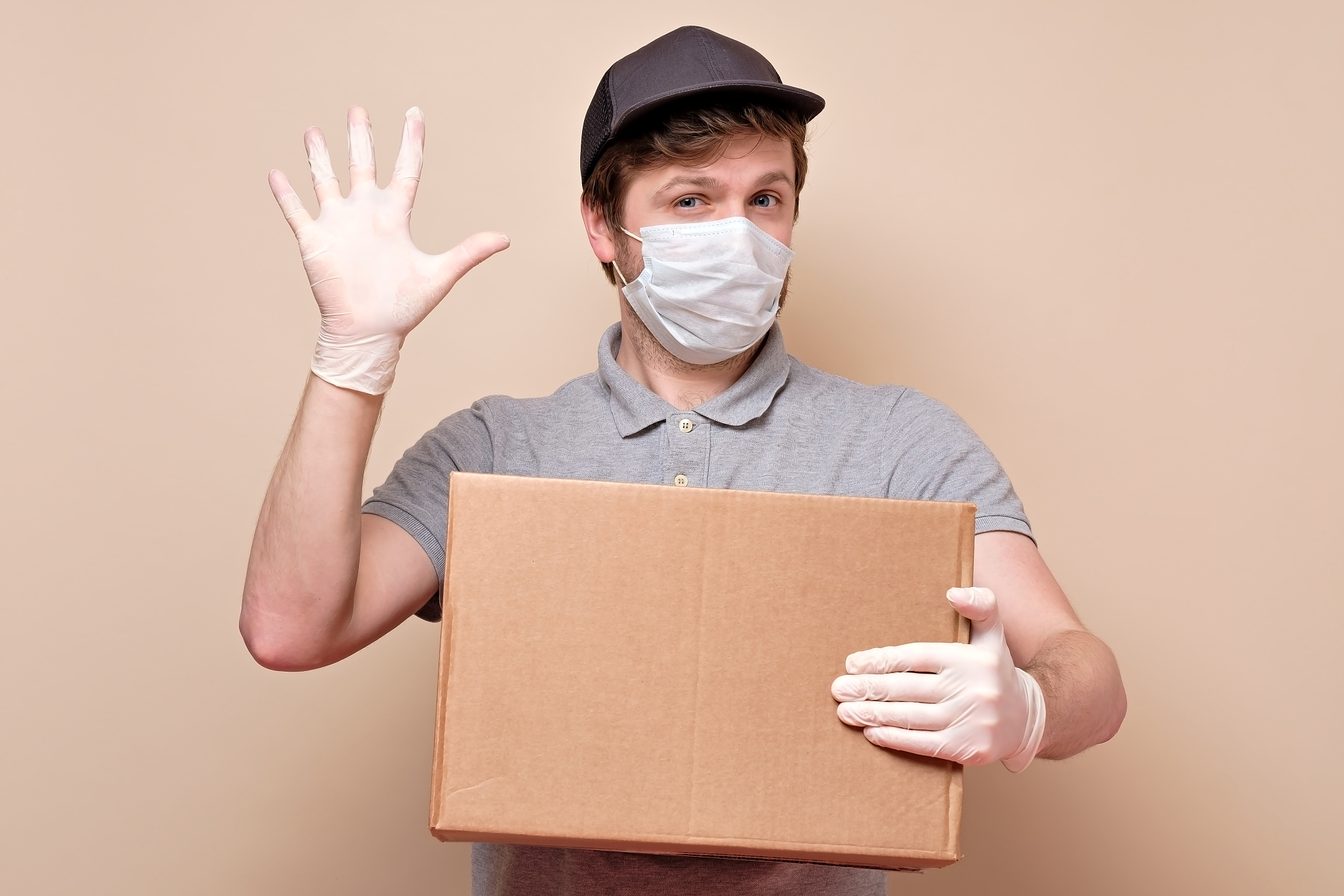 young delivery man in medical mask showing five finger holding a