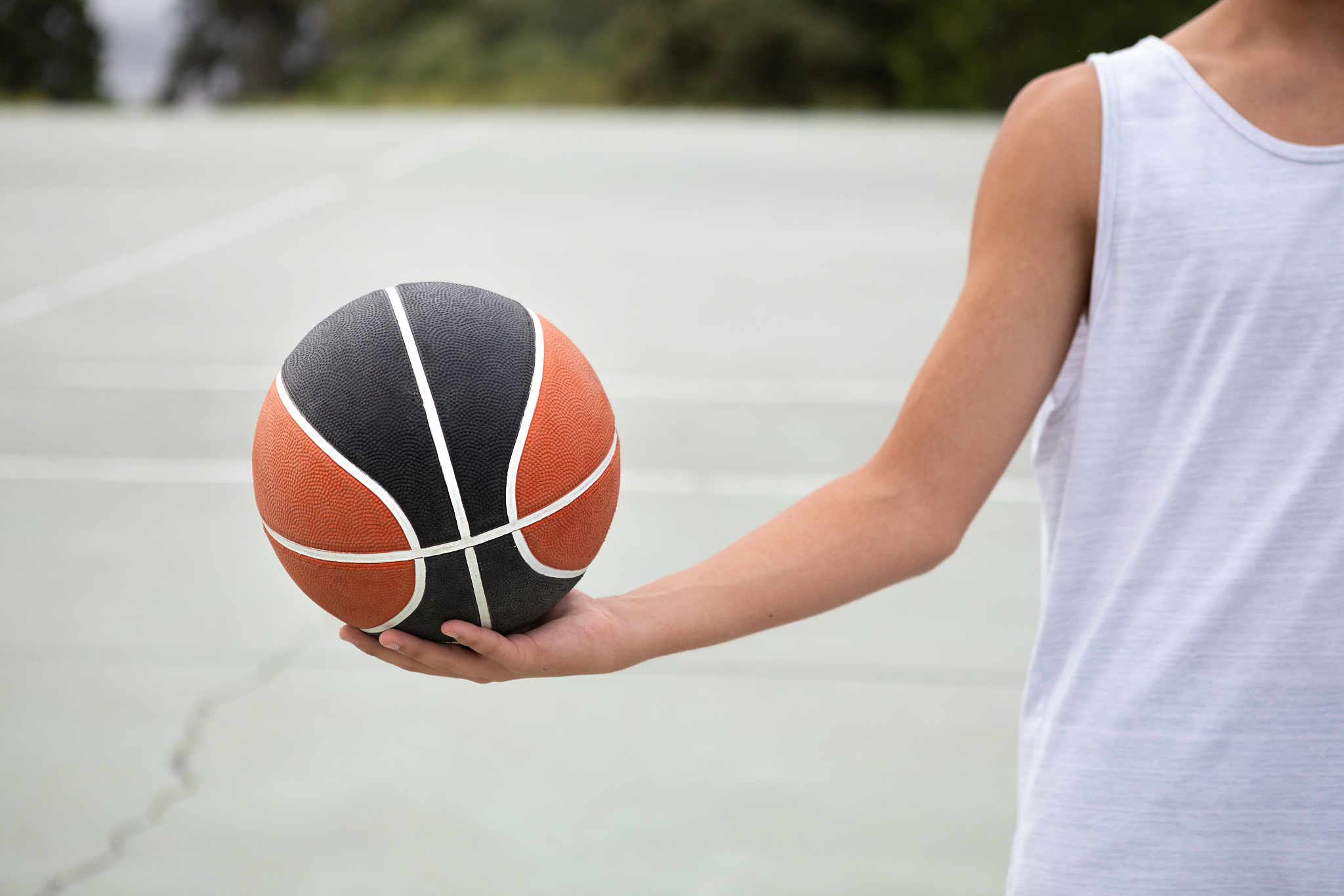 male teenage basketball player holding ball on basketball court,