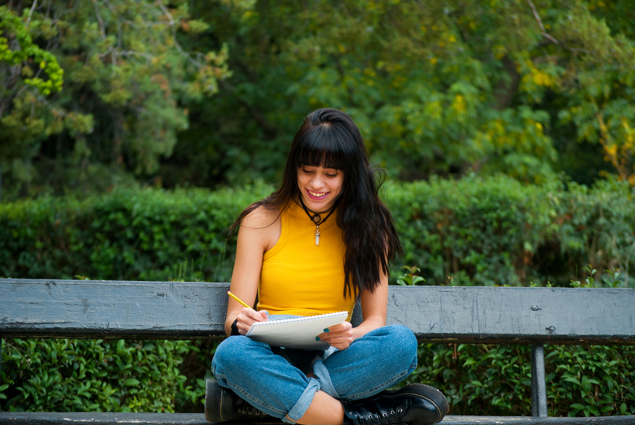 smiling young woman writing in book while sitting on bench, zara