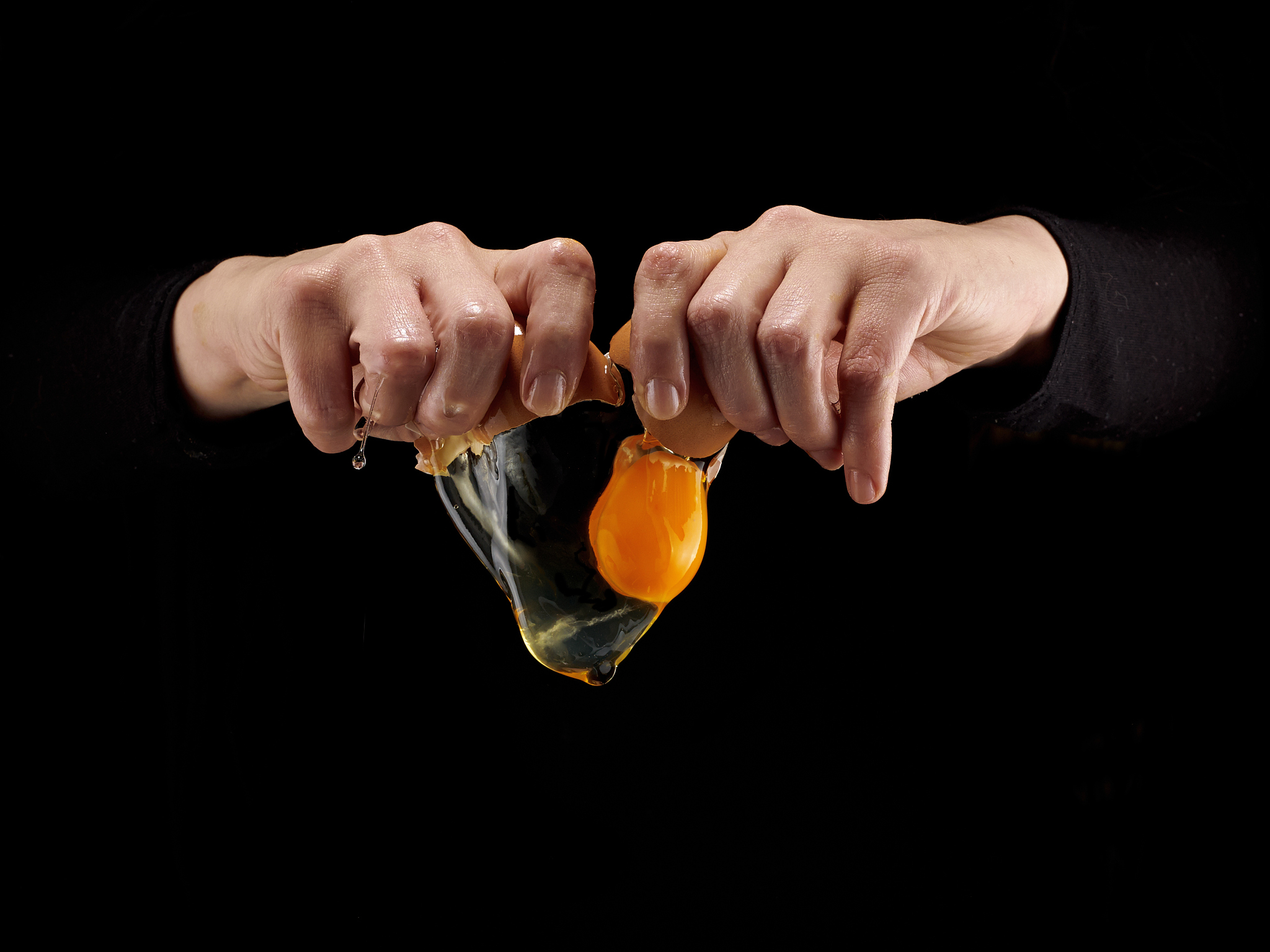 hands breaking an egg.