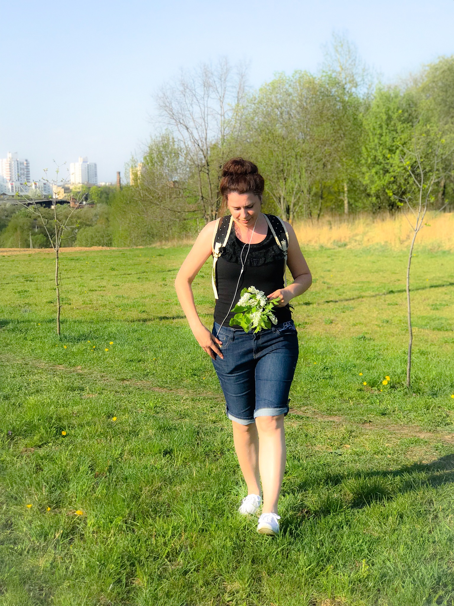the girl walks through a spring meadow, holding a bouquet of flo