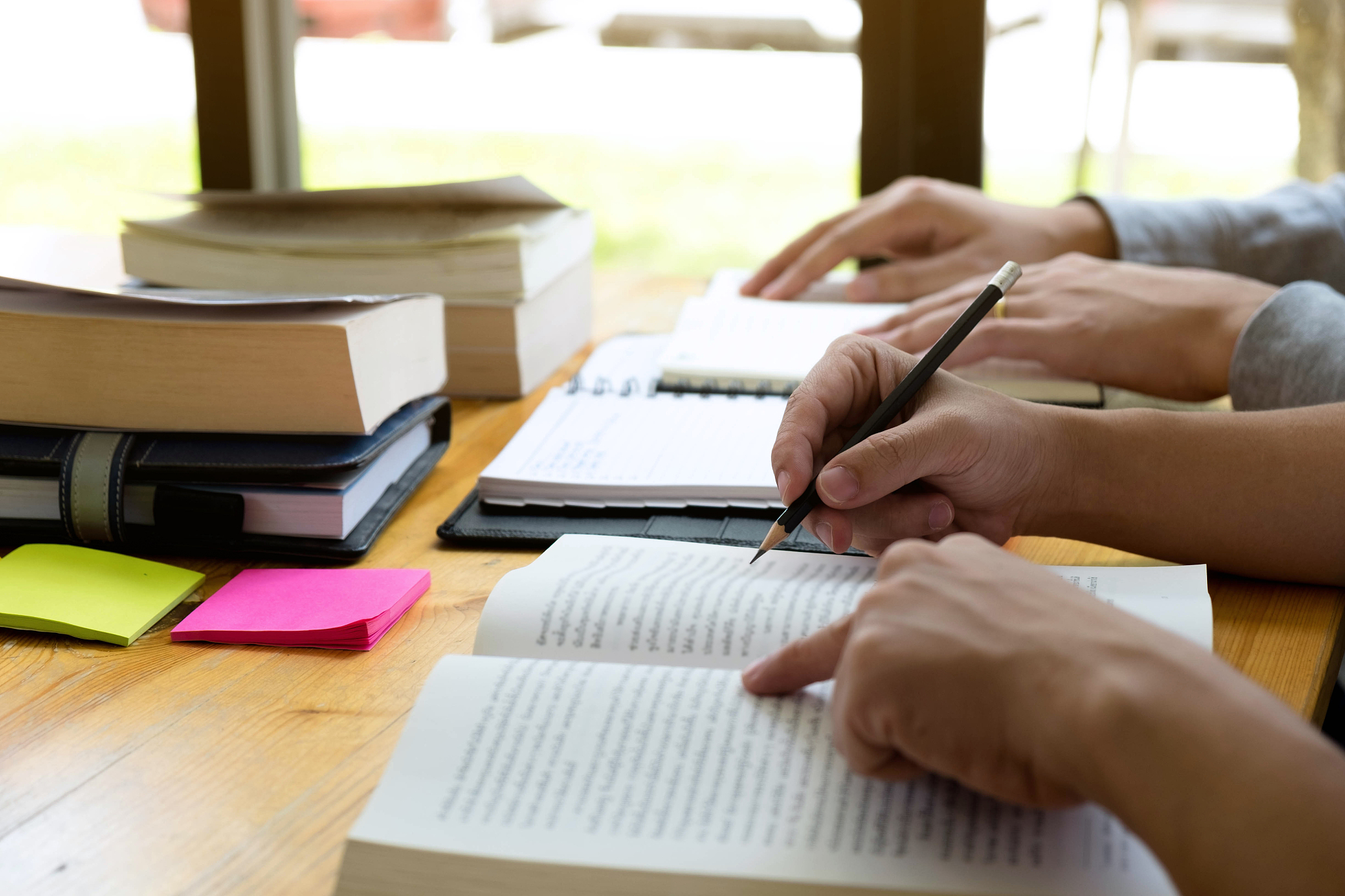 cropped image of students studying on table