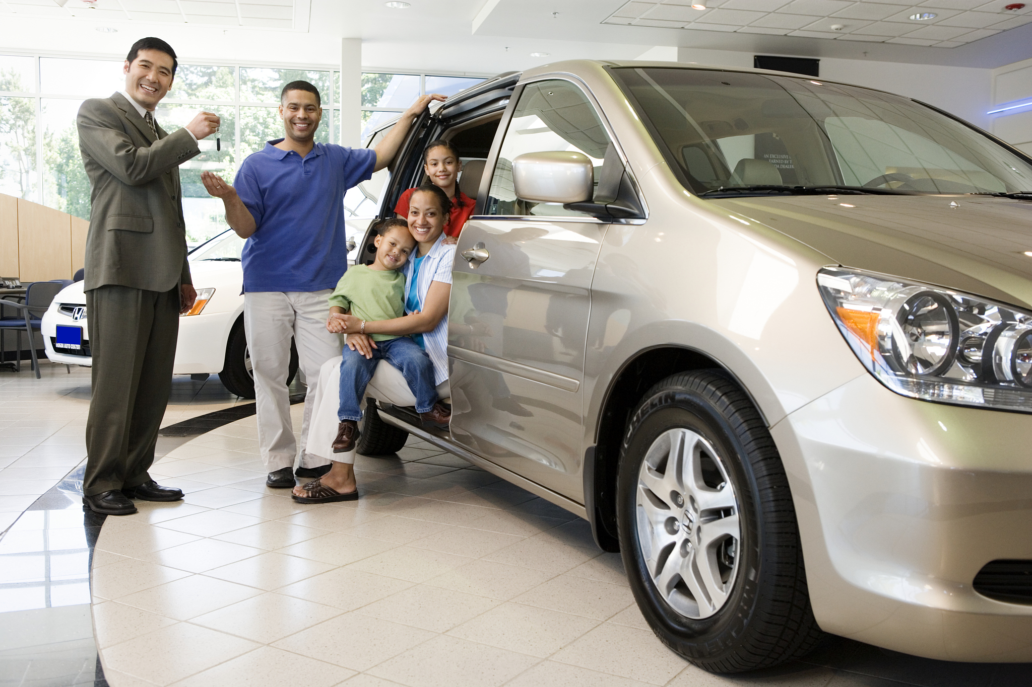 car salesman handing keys to family