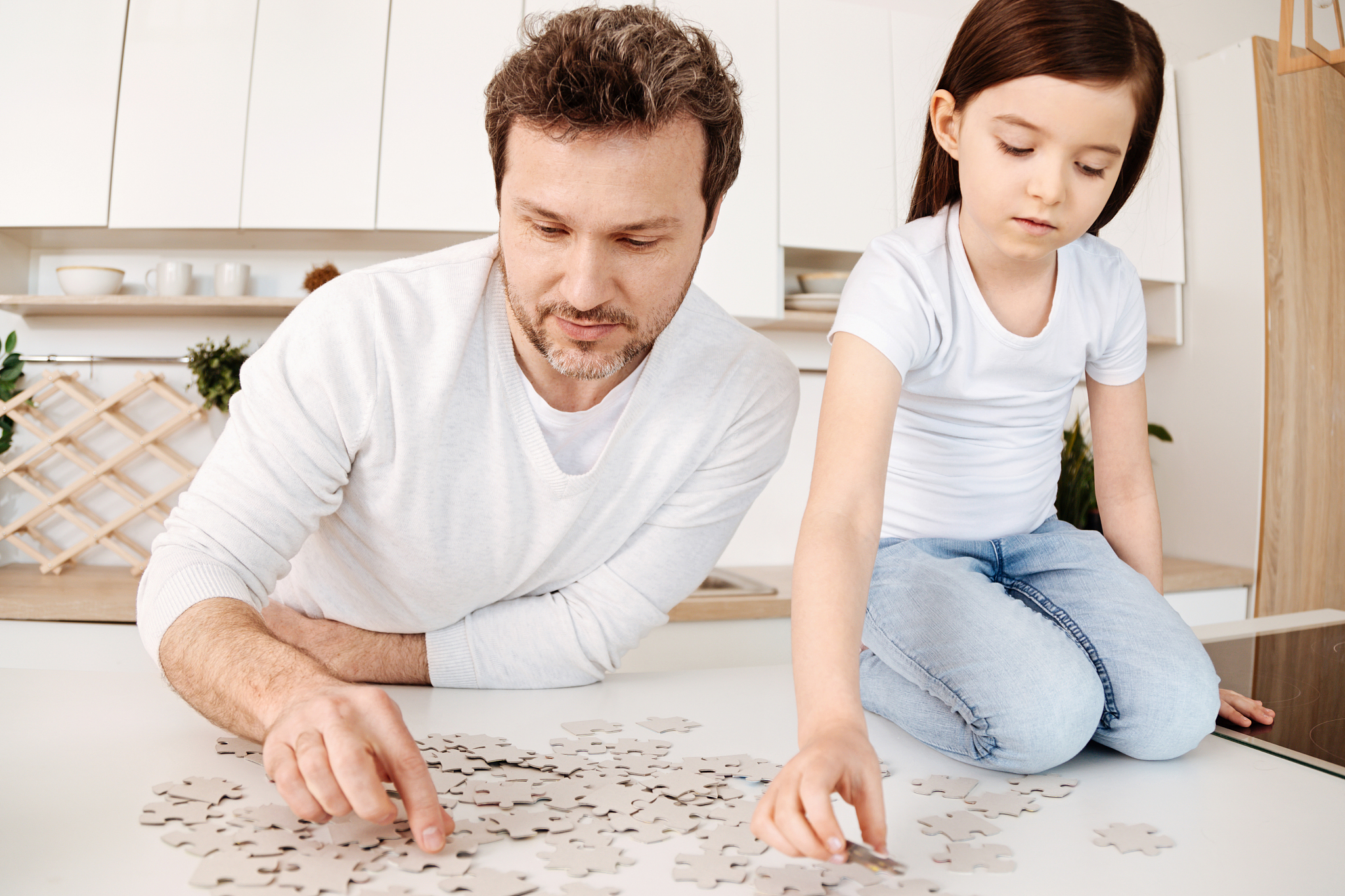 father and daughter doing a jigsaw puzzle in the kitchen