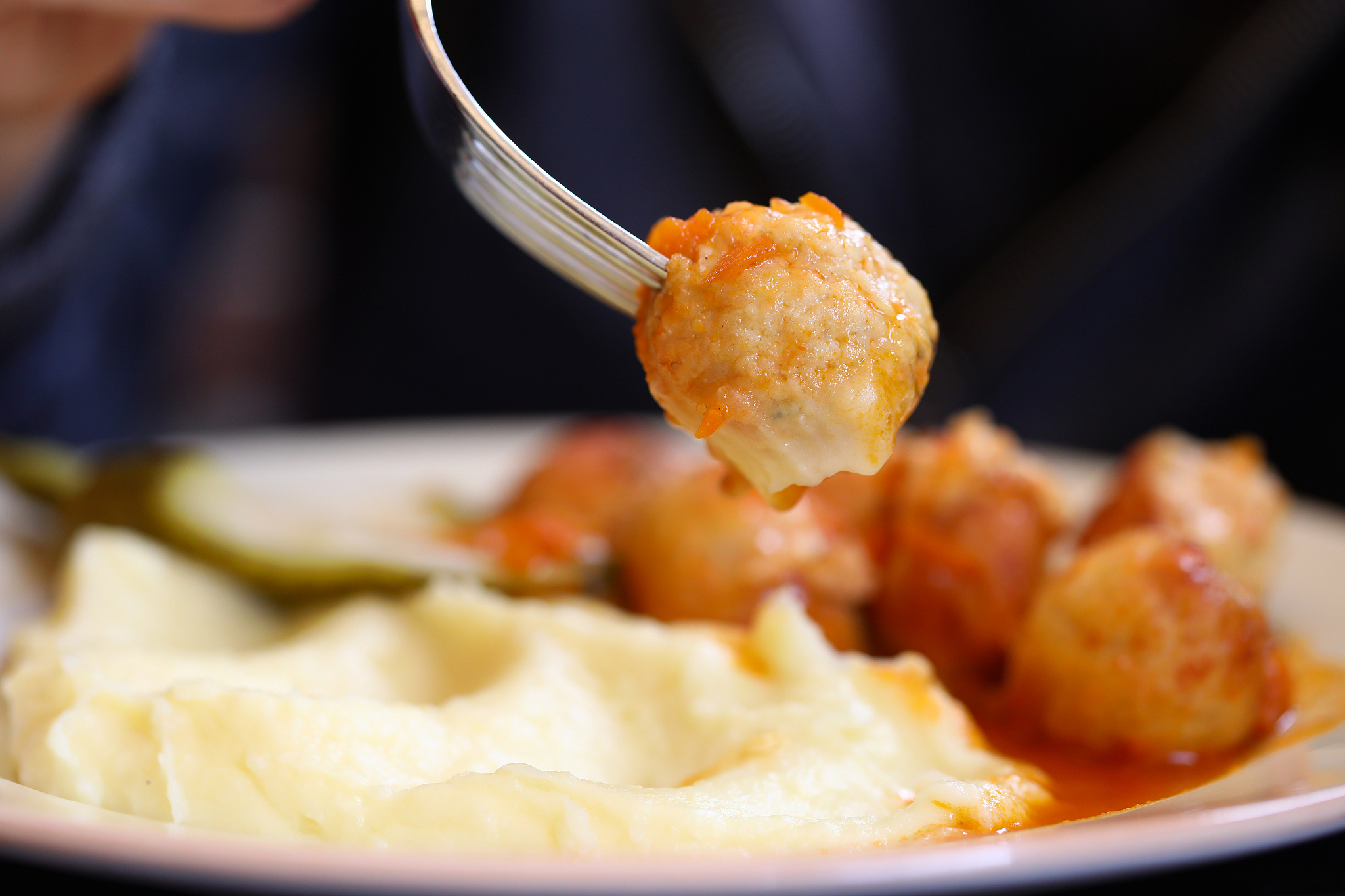 dish of meatballs mashed potatoes and pickles