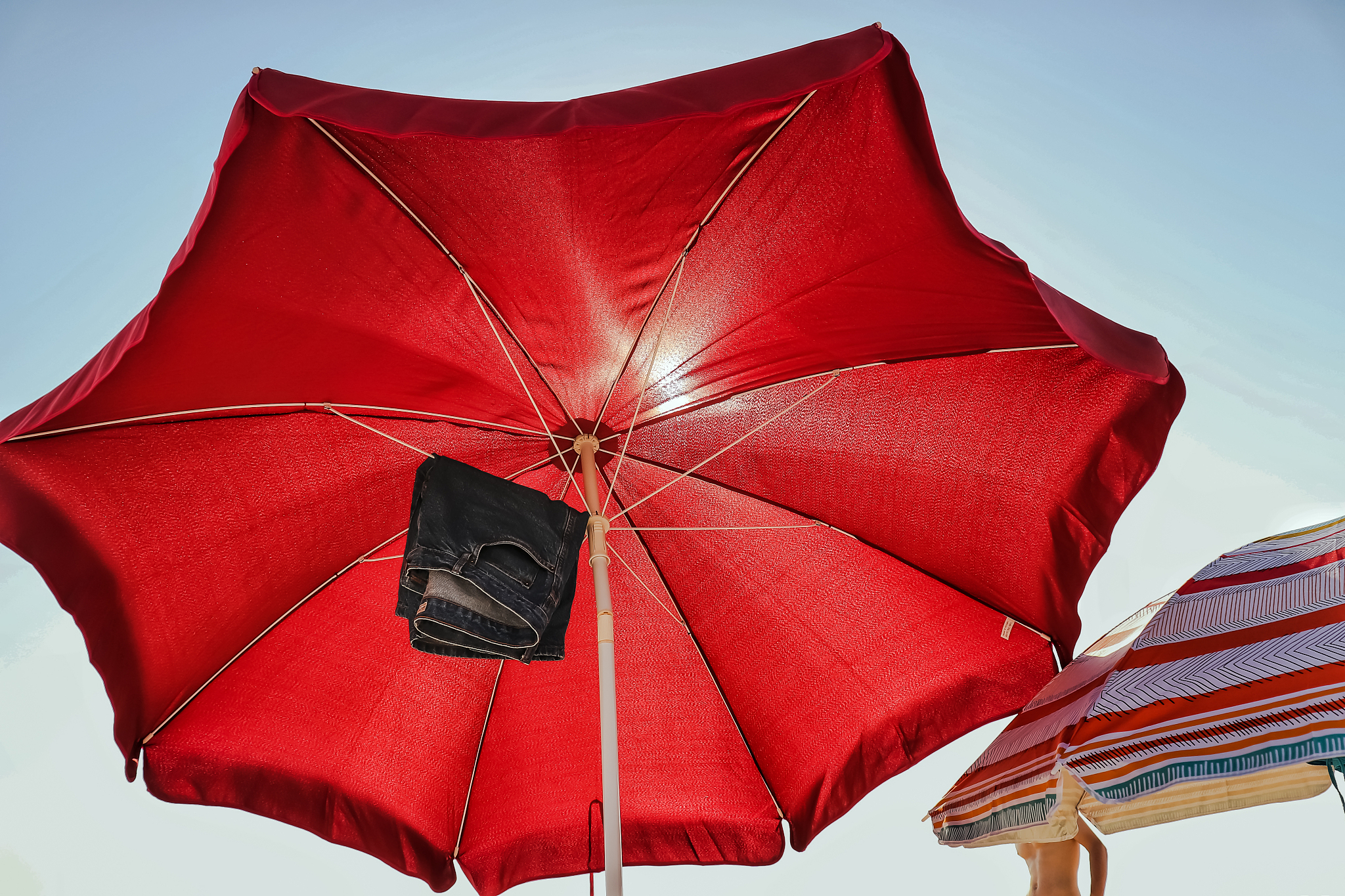 low angle view of hot pants hanging on red parasol against clear
