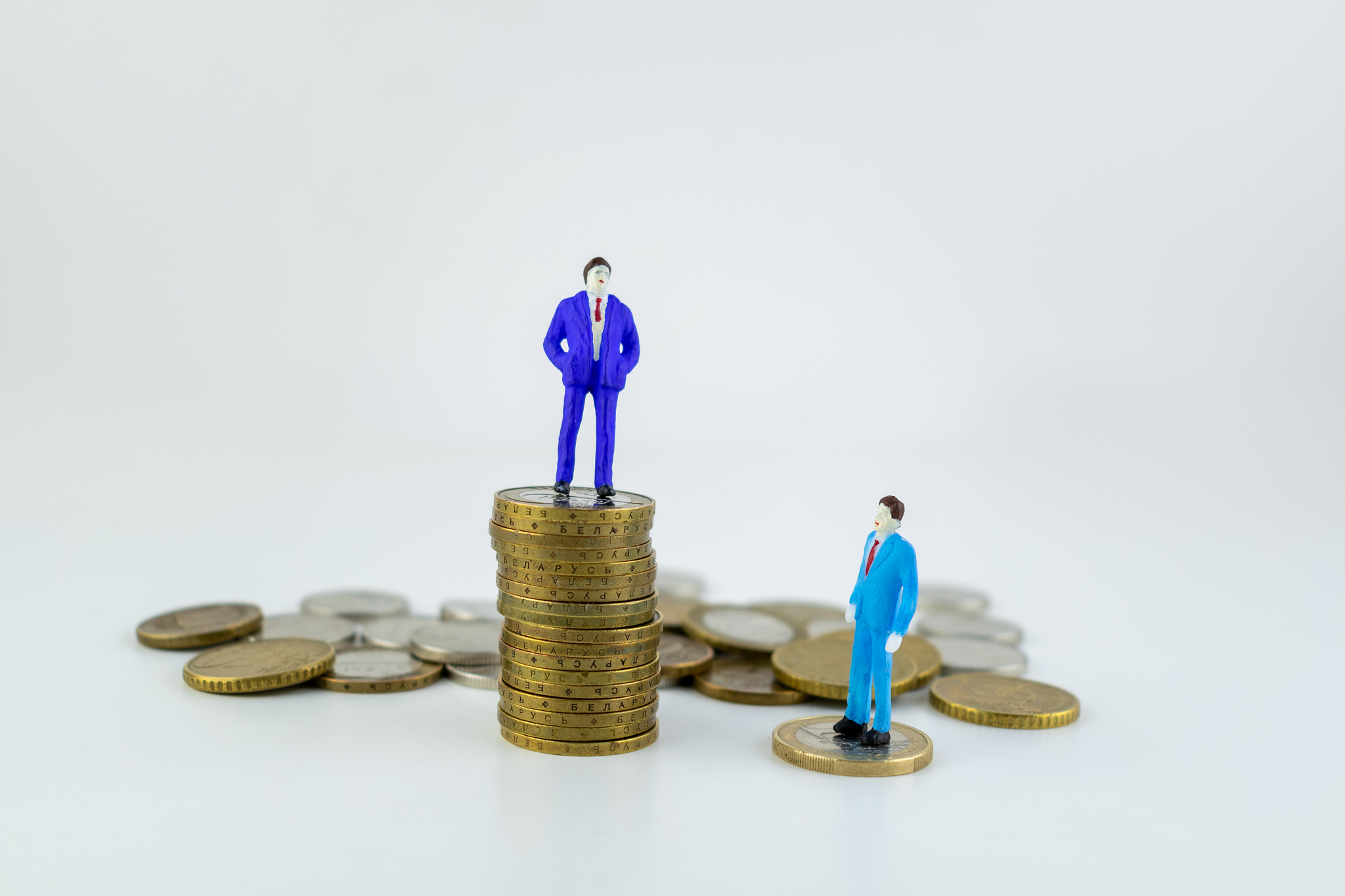 miniature people: small businessman standing on stack of coins a