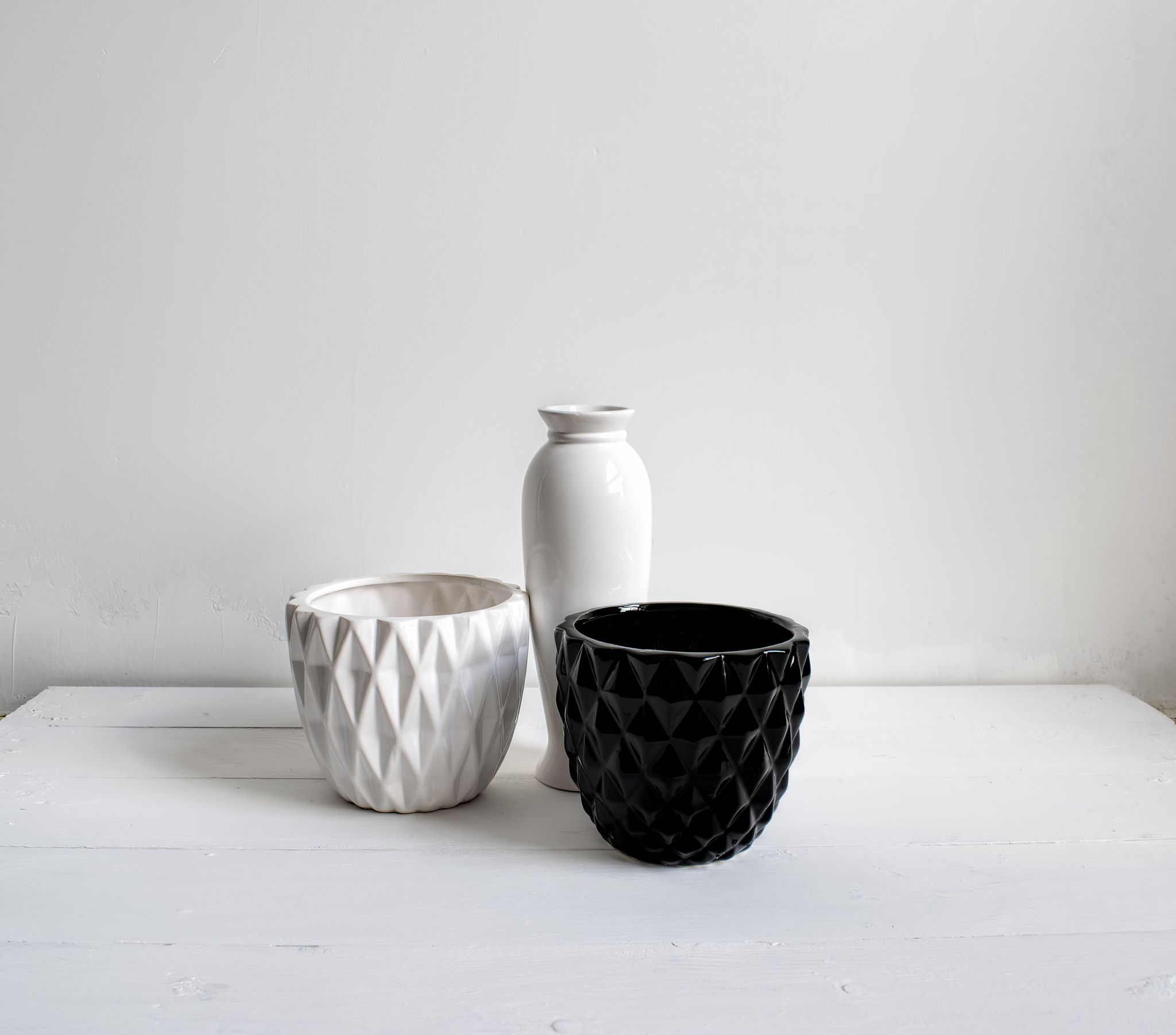 vase, black-and-white pots on wood table. white wall, background