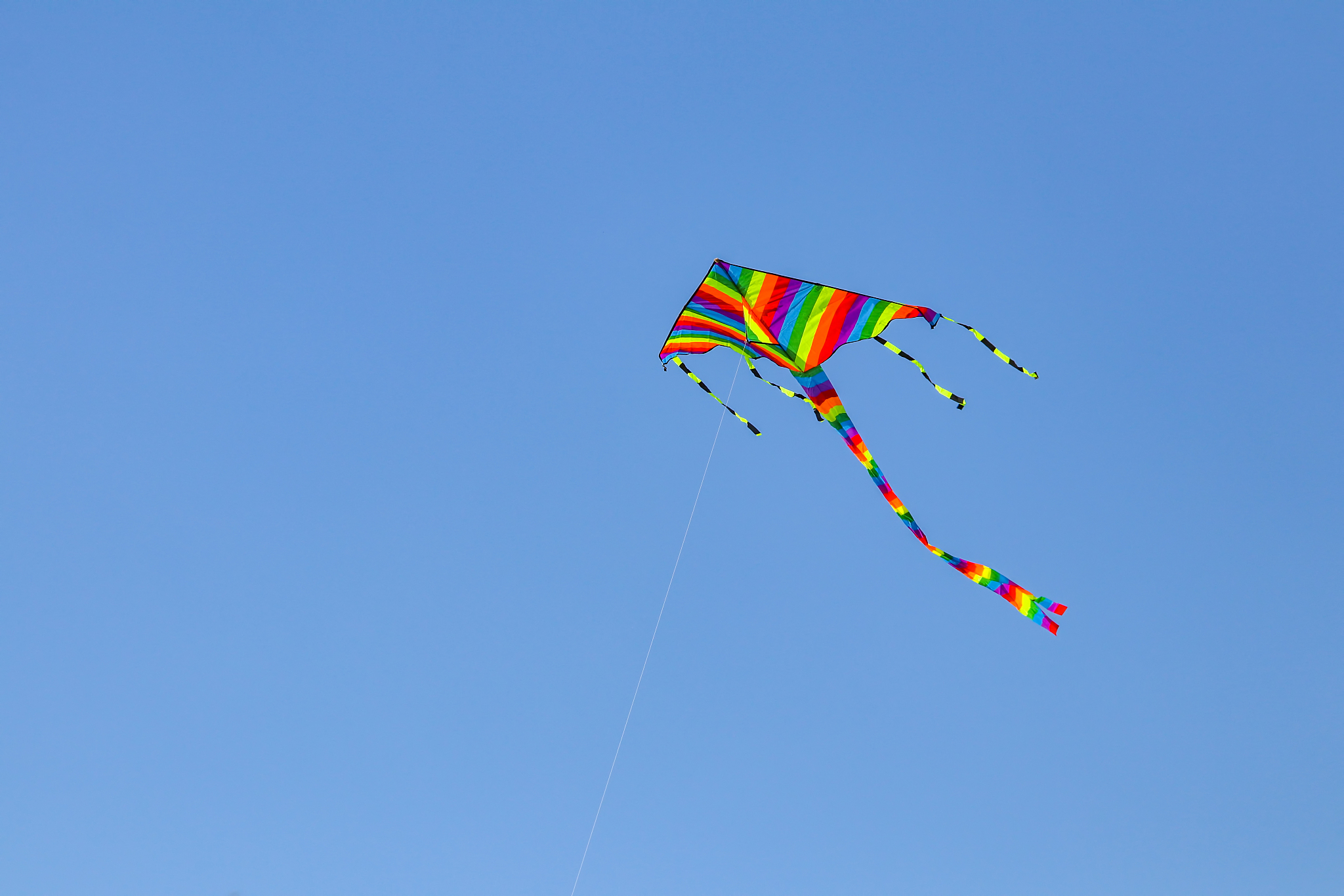 colorful kite flying in the blue sky with wind.
