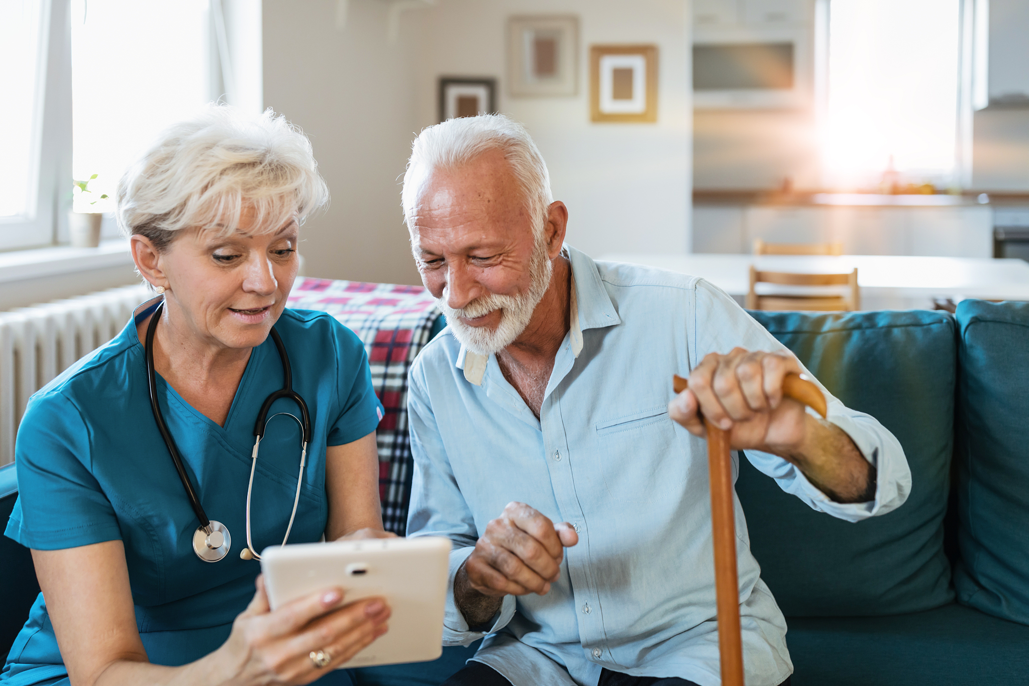 mature caregiver watching movie on tablet with old man while sit