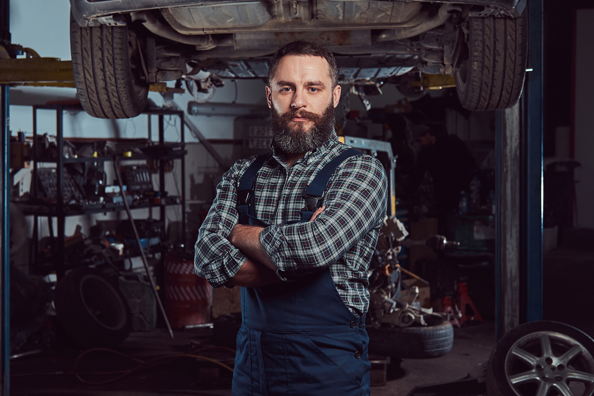 two bearded brutal mechanics repair a car on a lift in the garag