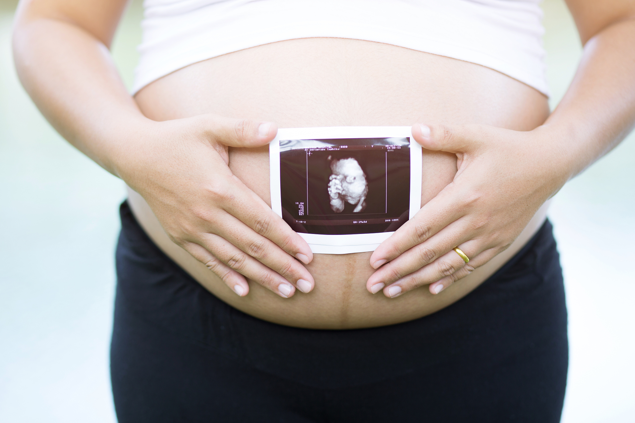 midsection of pregnant woman holding ultrasound on stomach