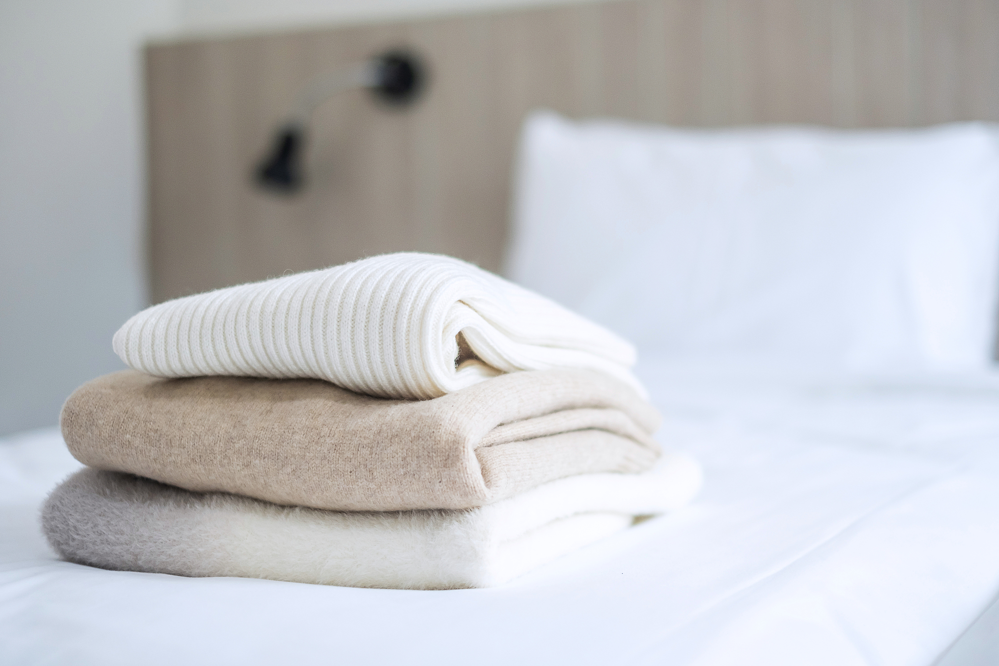 stack of beige wool sweaters on bed in luxury hotel or resort or