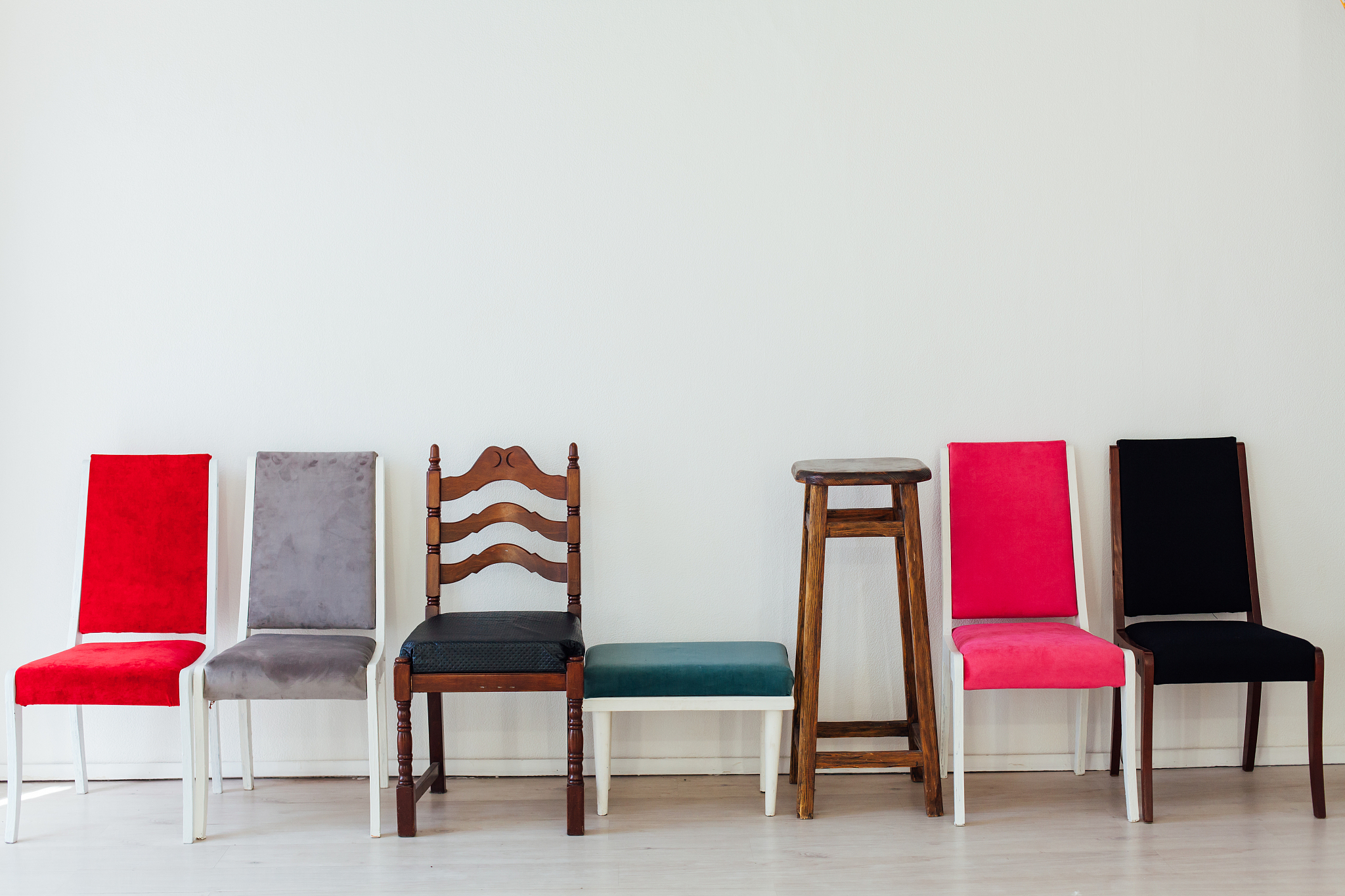 many different chairs stand in the white room