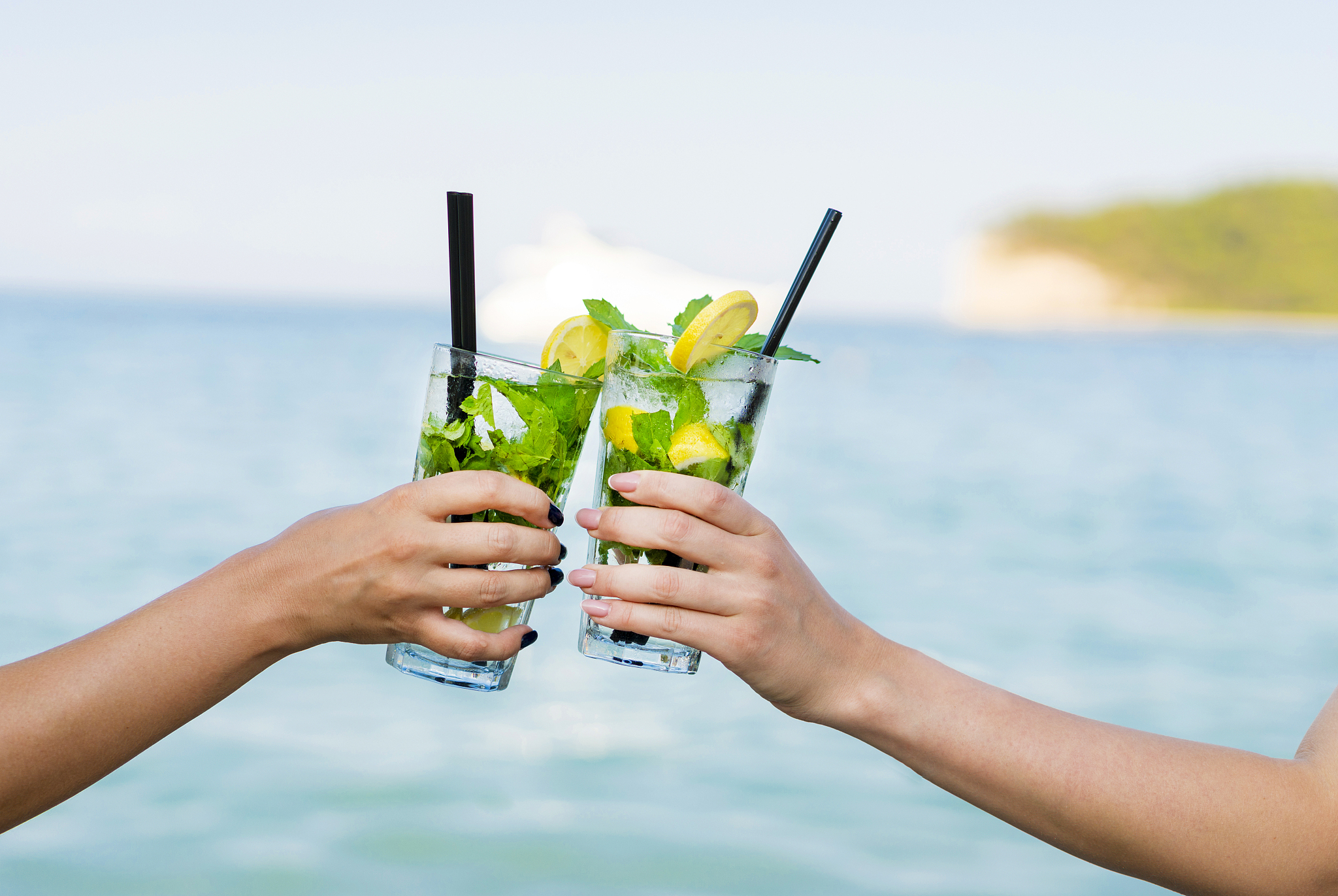 hands holding mojito drinks