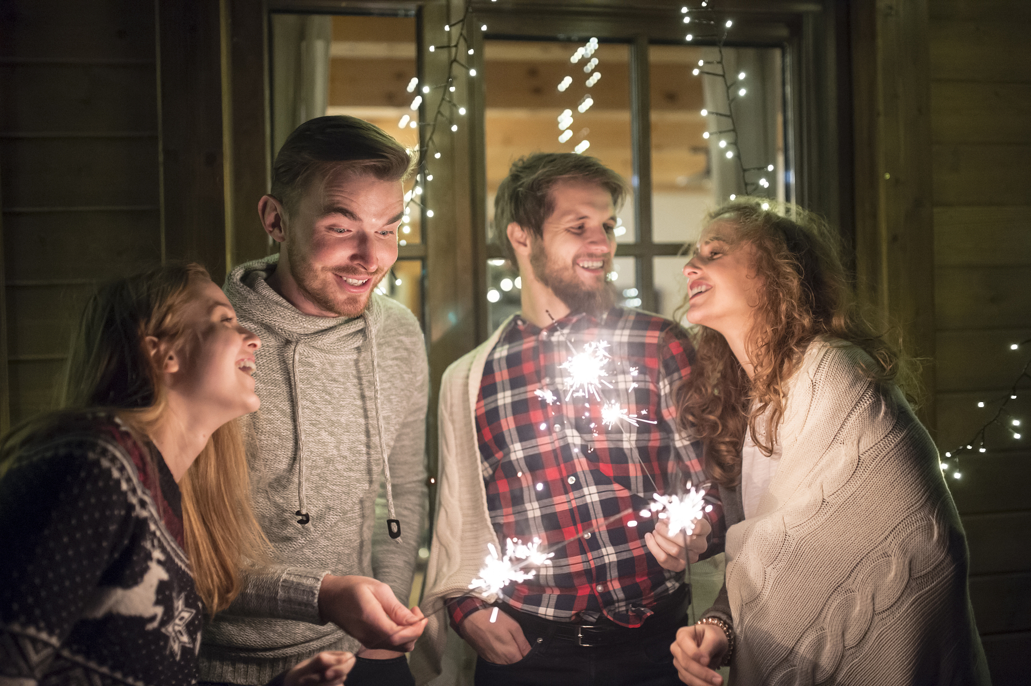 happy friends holding sparklers outdoors at night
