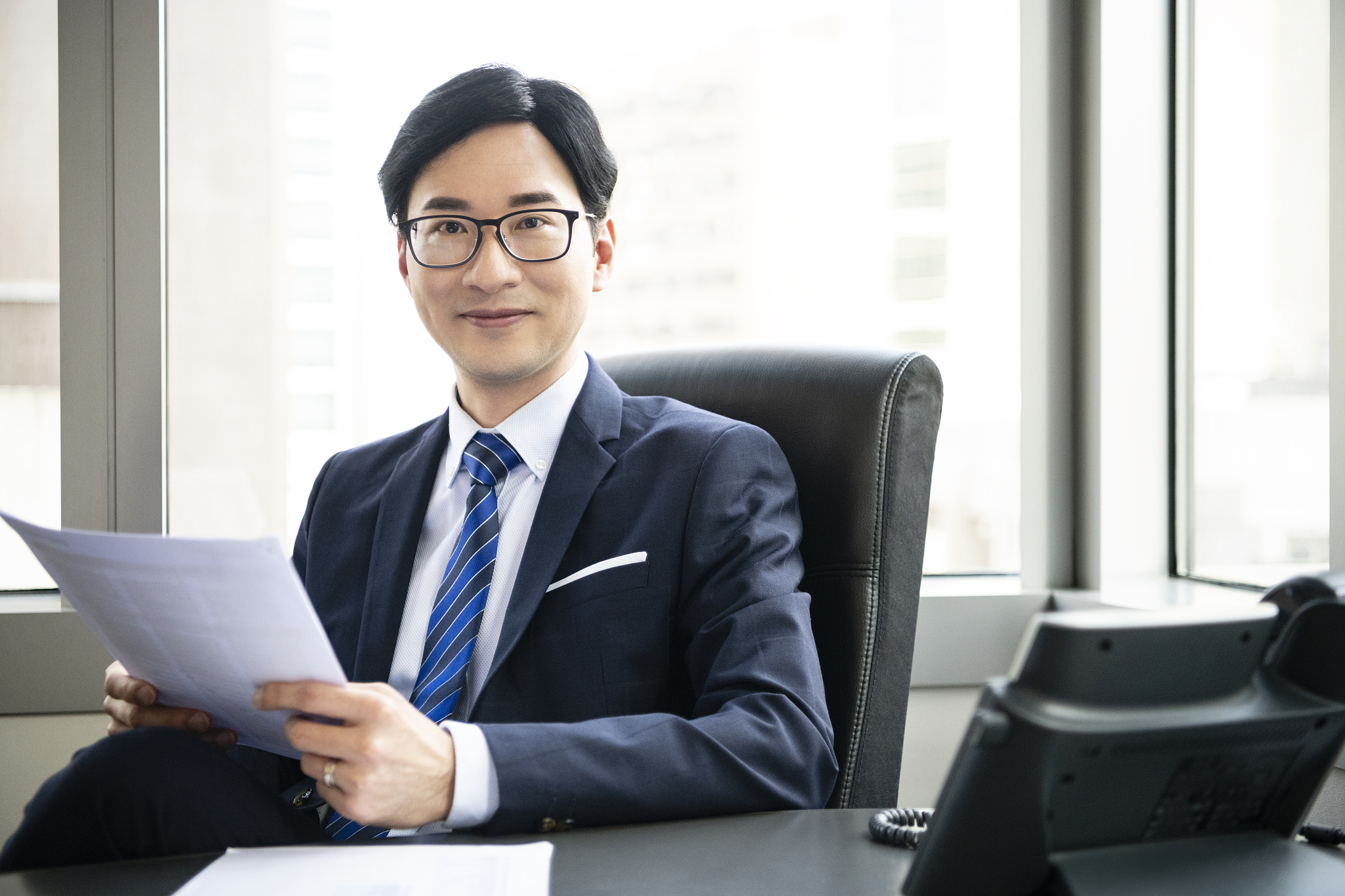 cheerful chinese businessman in office with document