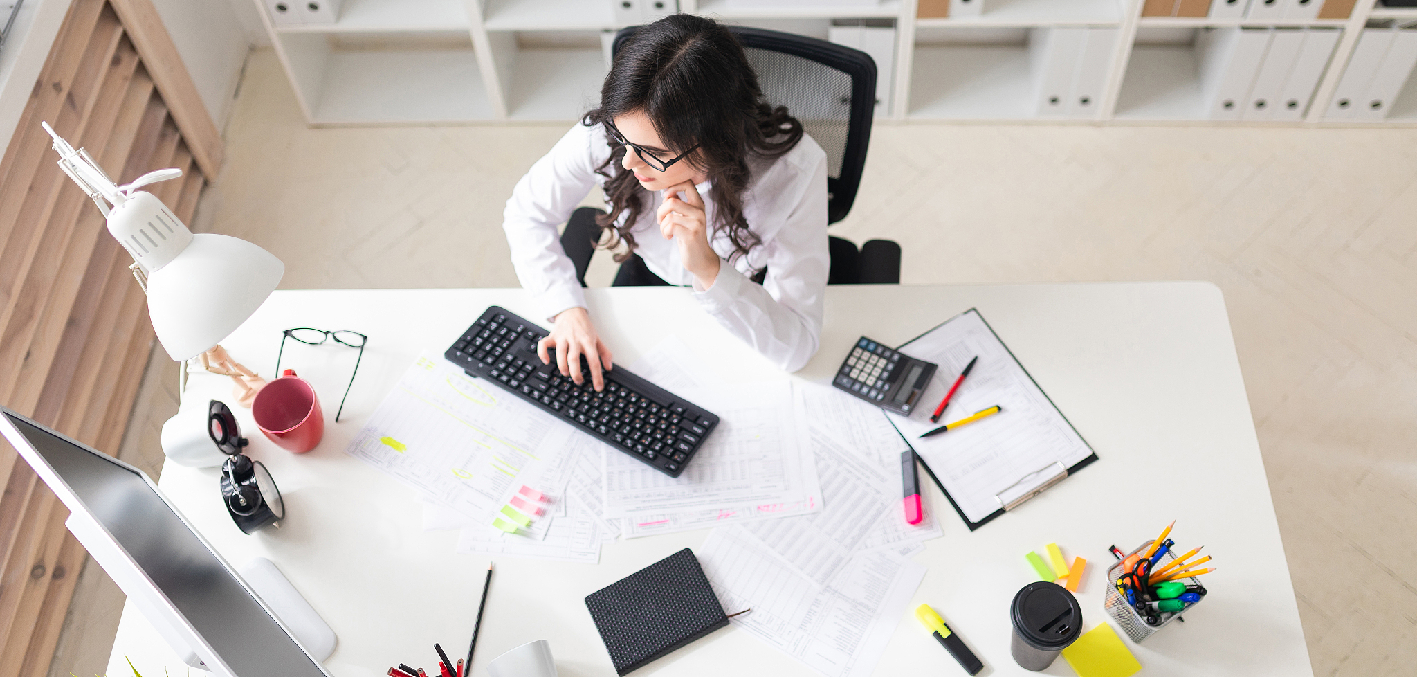 a young girl is sitting in the office at the computer and workin
