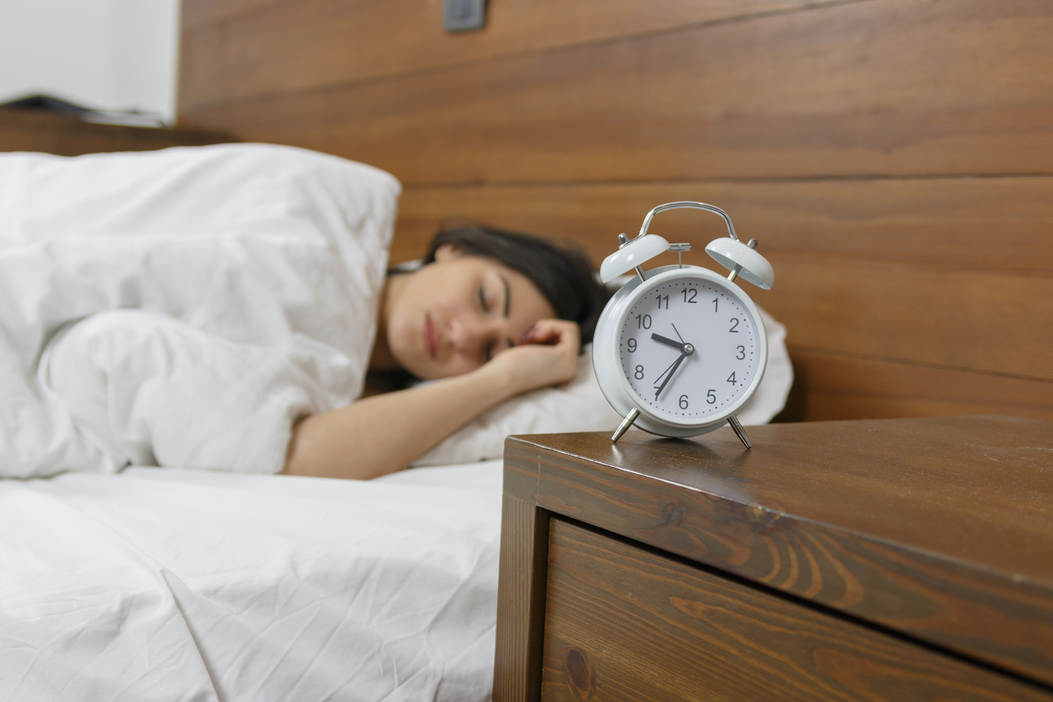 young beautiful woman sleeping in bed under white blanket