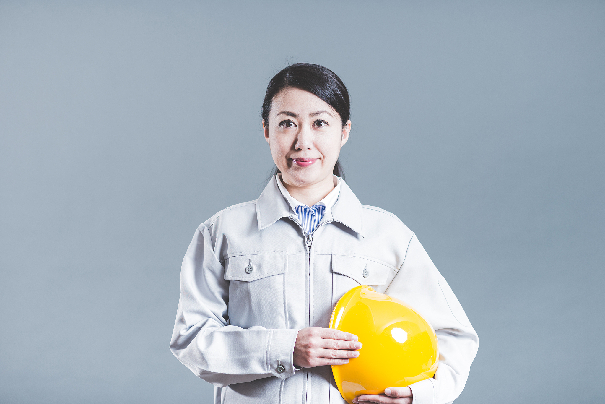 women standing wearing work clothes with a gray background