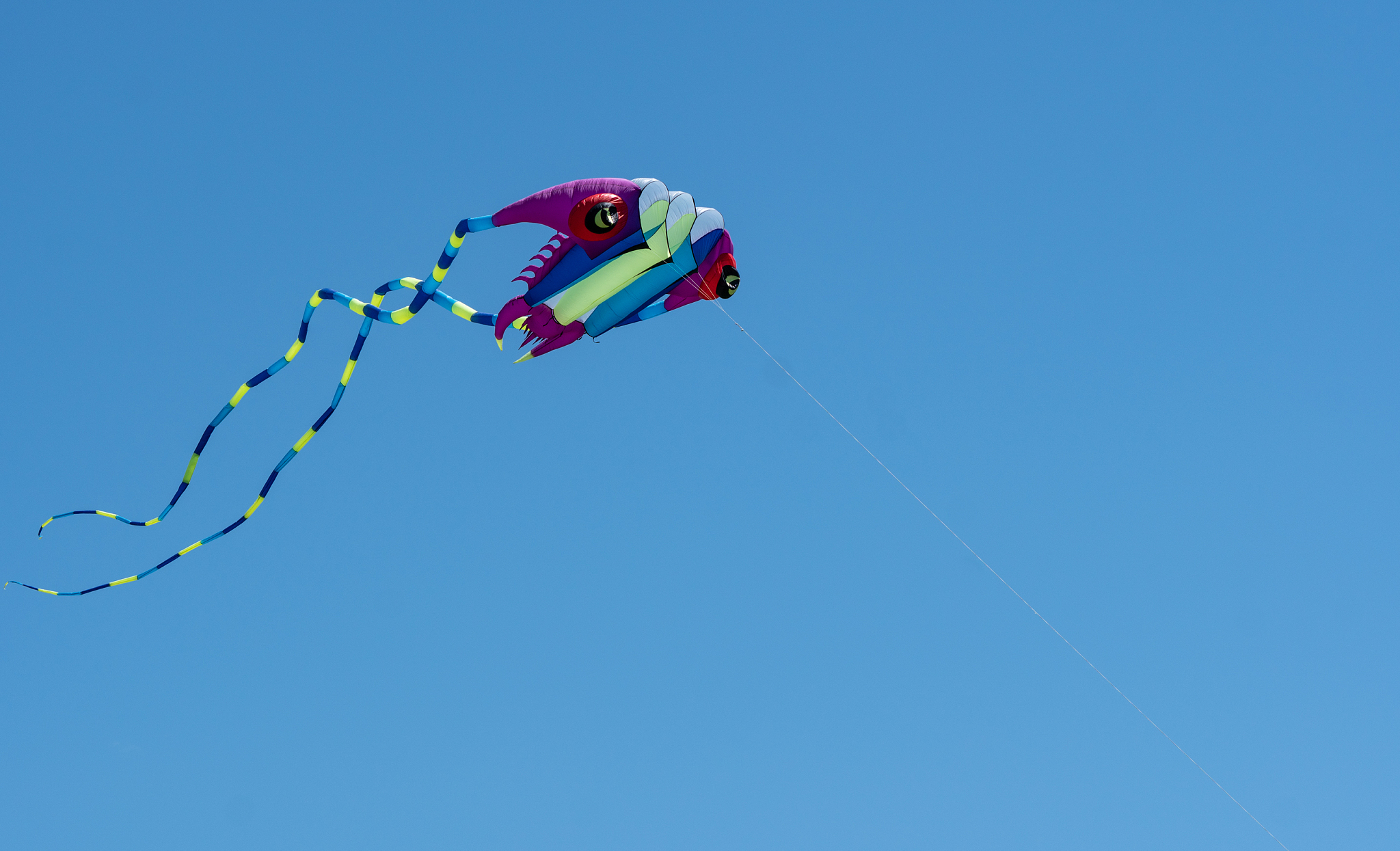 colorful kite with long tail against blue sky background.