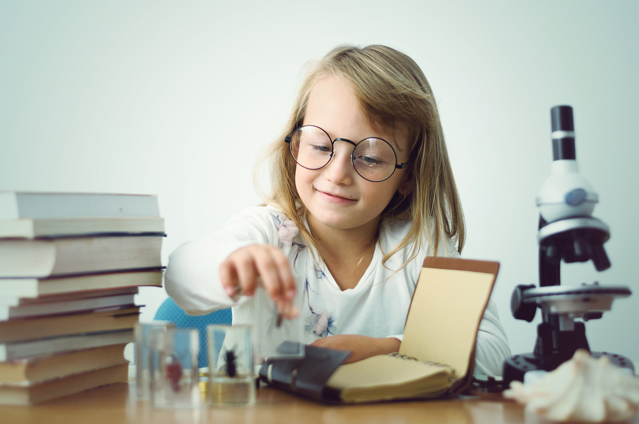 little girl playing scientist among stacks of books with a micro