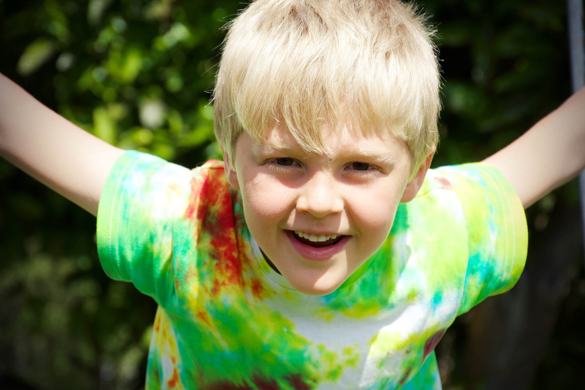 child wearing tie dye t-shirt plays in garden