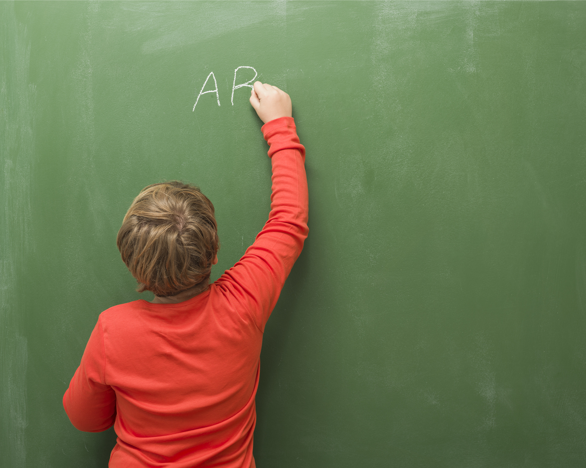 back view of little boy writing on blank blackboard