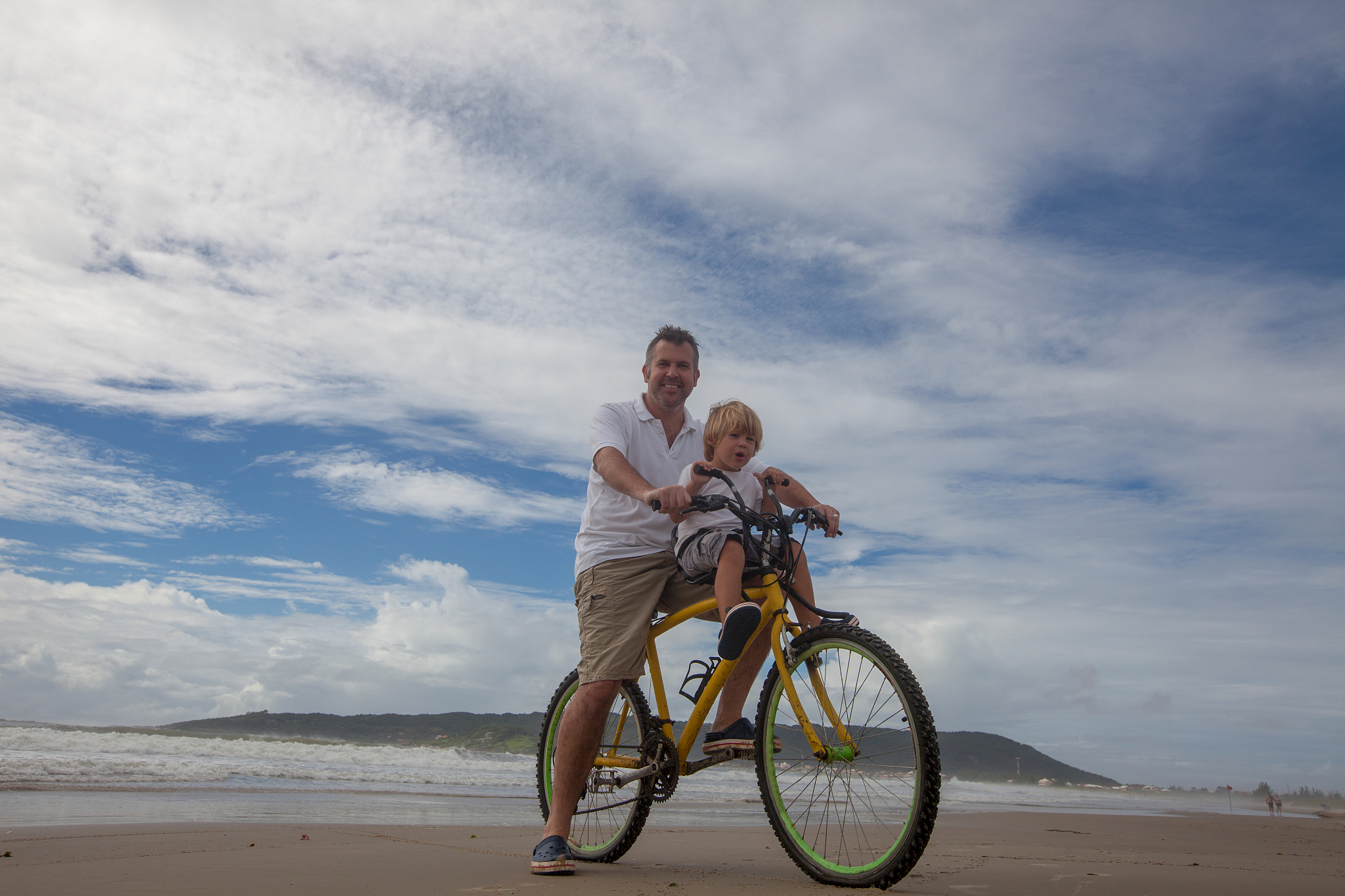 father and son on bicycle at beach